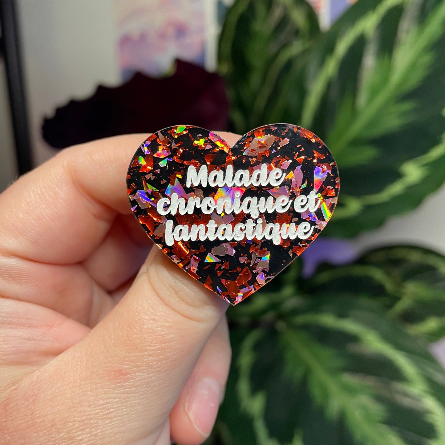 Broche "Malade chronique et fantastique" en acrylique noire avec des éclats de confettis rouges et roses