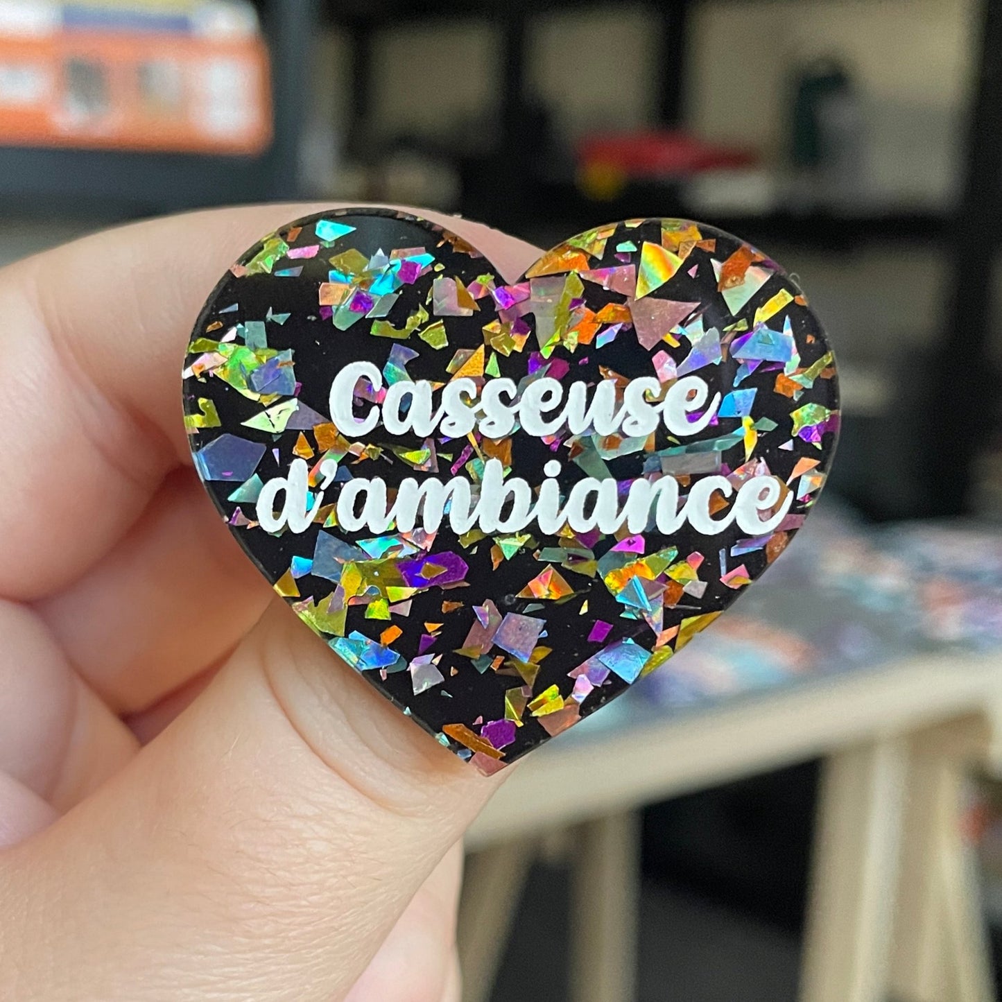 Broche "Casseuse d'ambiance" en acrylique noire avec des éclats de confettis multicolores