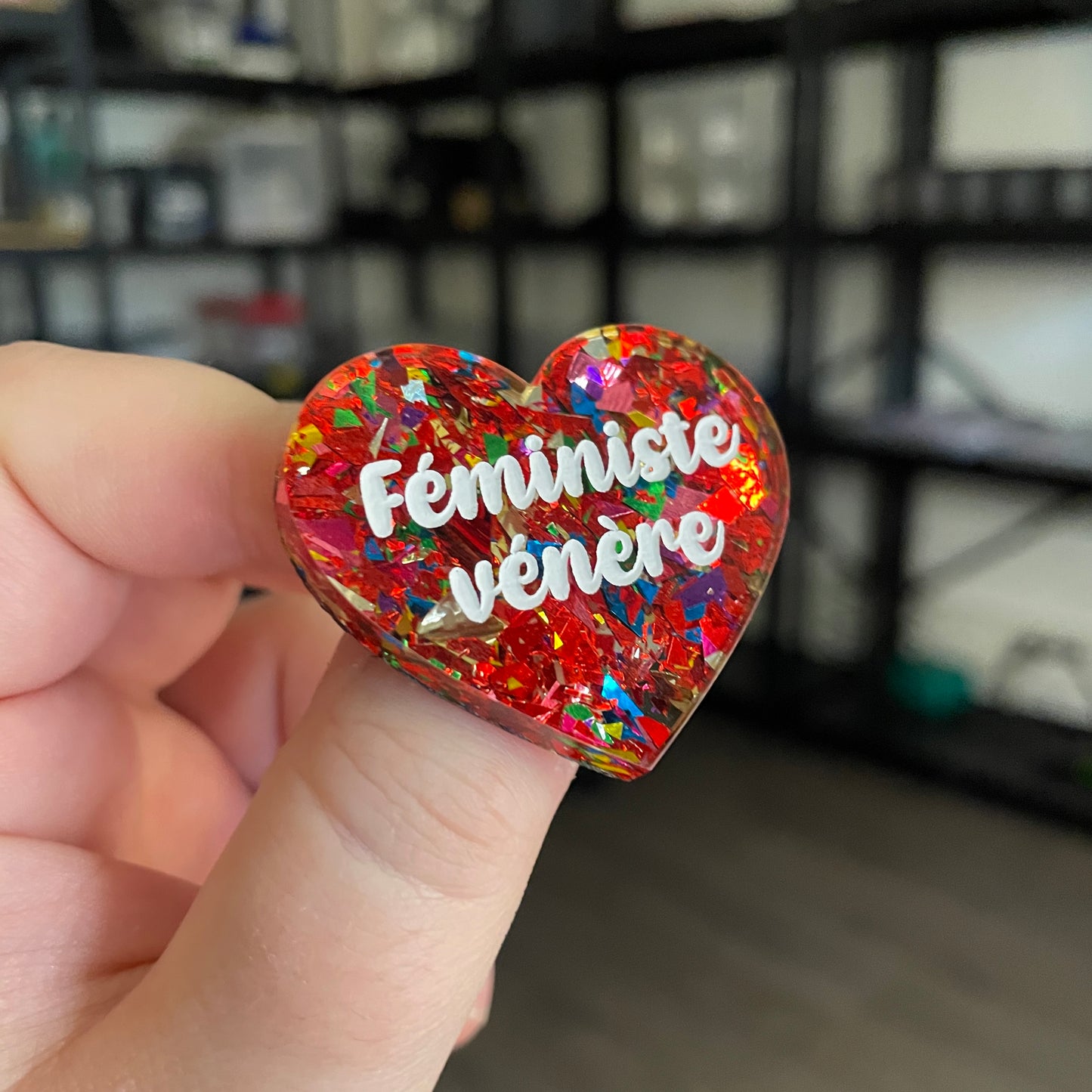 Broche "Féministe vénère" en acrylique transparente avec des éclats de confettis rouges et multicolores