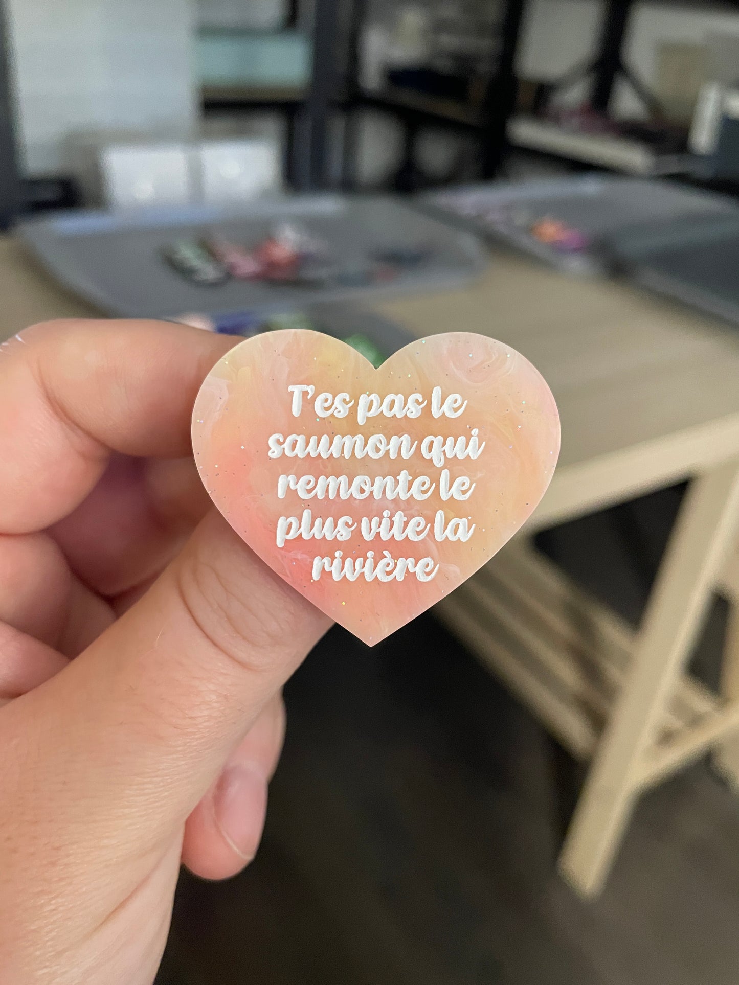 Broche "T'es pas le saumon qui remonte le plus vite la rivière" en acrylique marbrée semi-transparente orange, corail, blanche et jaune à paillettes