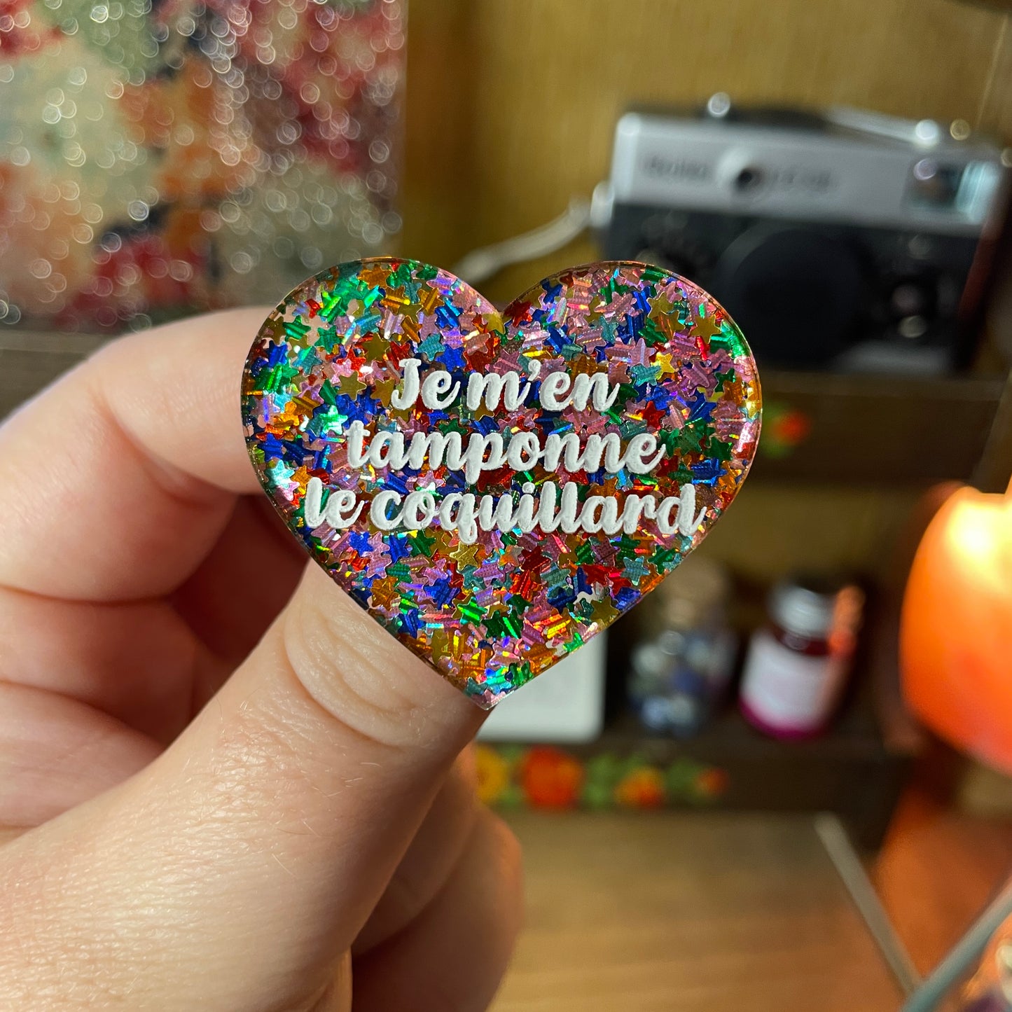 Broche "Je m'en tamponne le coquillard" en acrylique semi transparente avec des étoiles multicolores