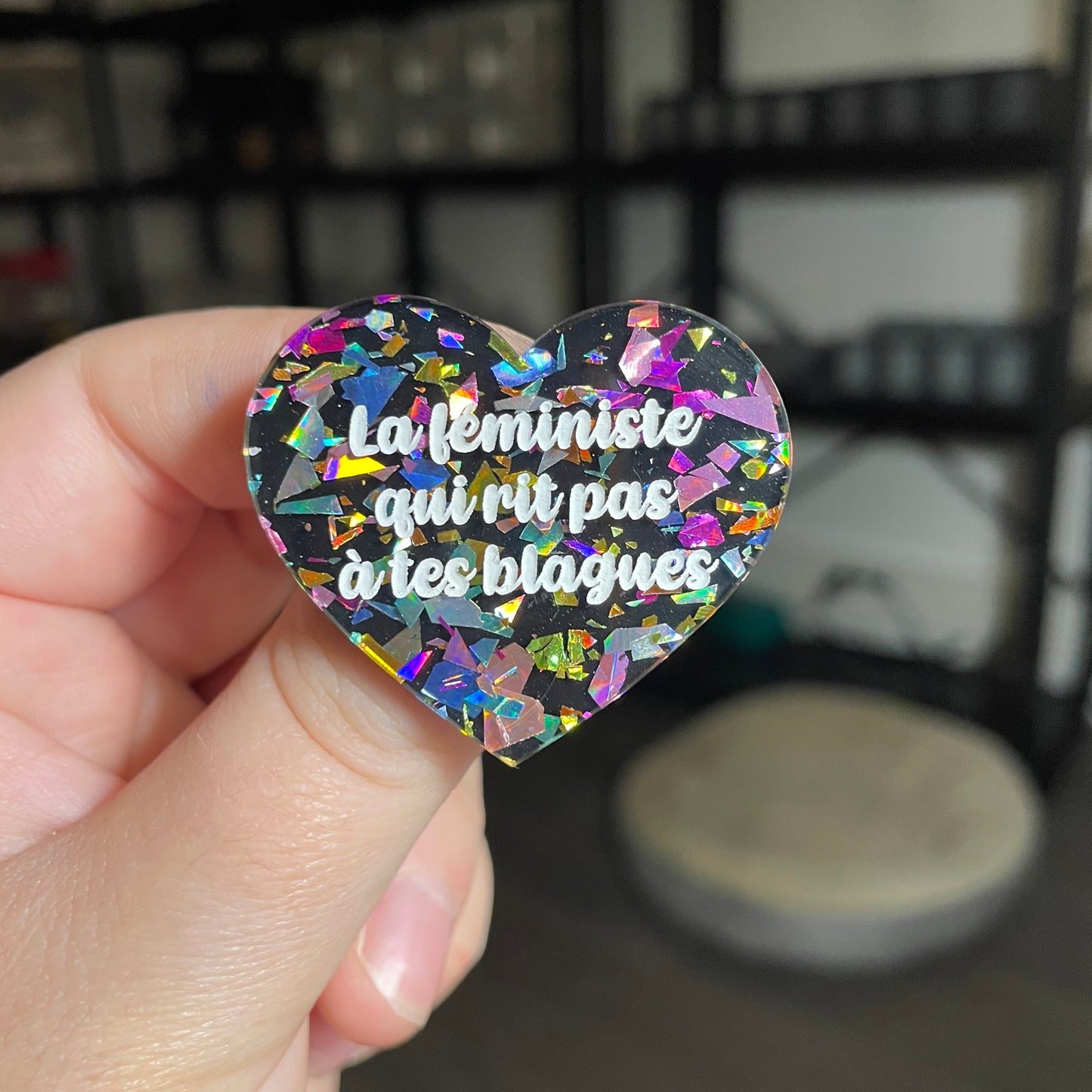 Broche "La féministe qui rit pas à tes blagues" en acrylique noire avec des éclats de confettis multicolores