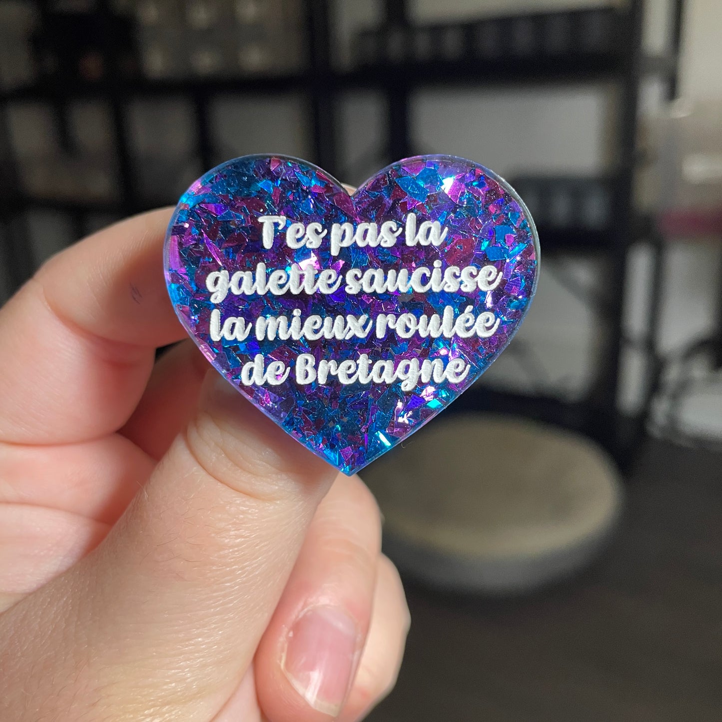 Broche "T'es pas la galette saucisse la mieux roulée de Bretagne" en acrylique transparente avec des paillettes bleues et violettes