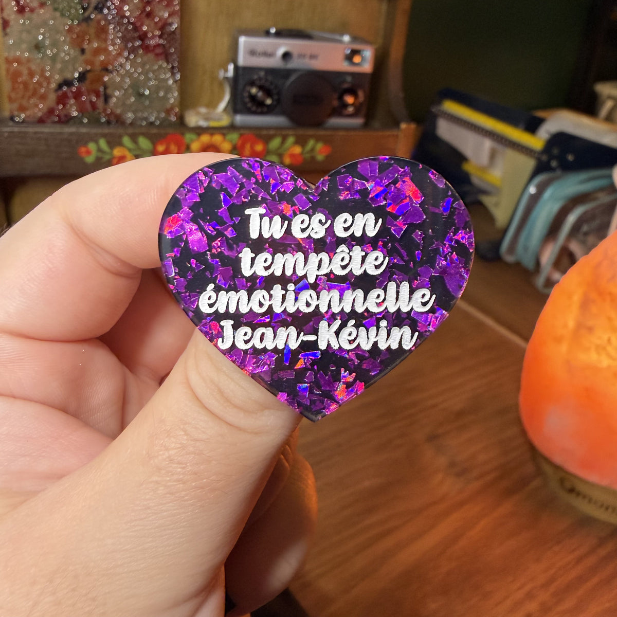 Broche "Tu es en tempête émotionnelle Jean-Kévin" en acrylique noire avec des éclats de confettis violets