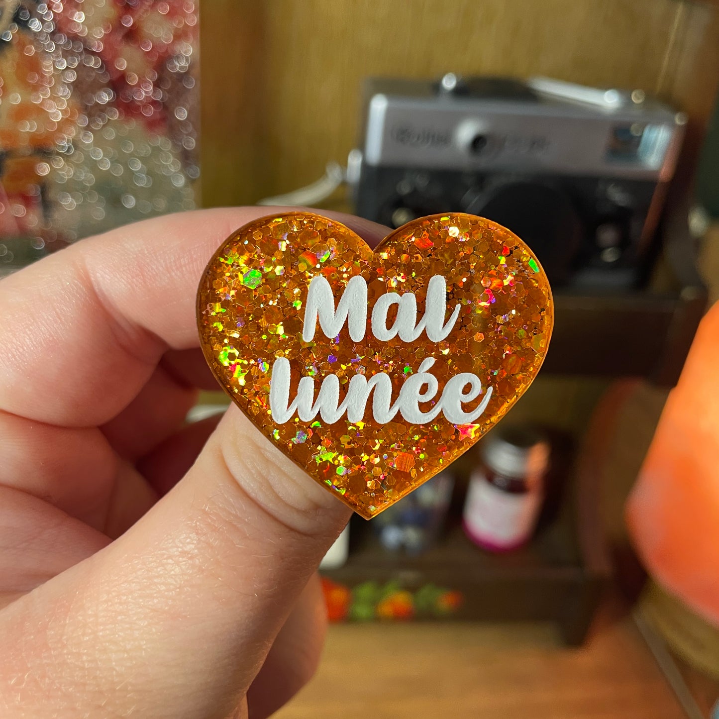 Broche "Mal lunée" en acrylique semi transparente à paillettes oranges