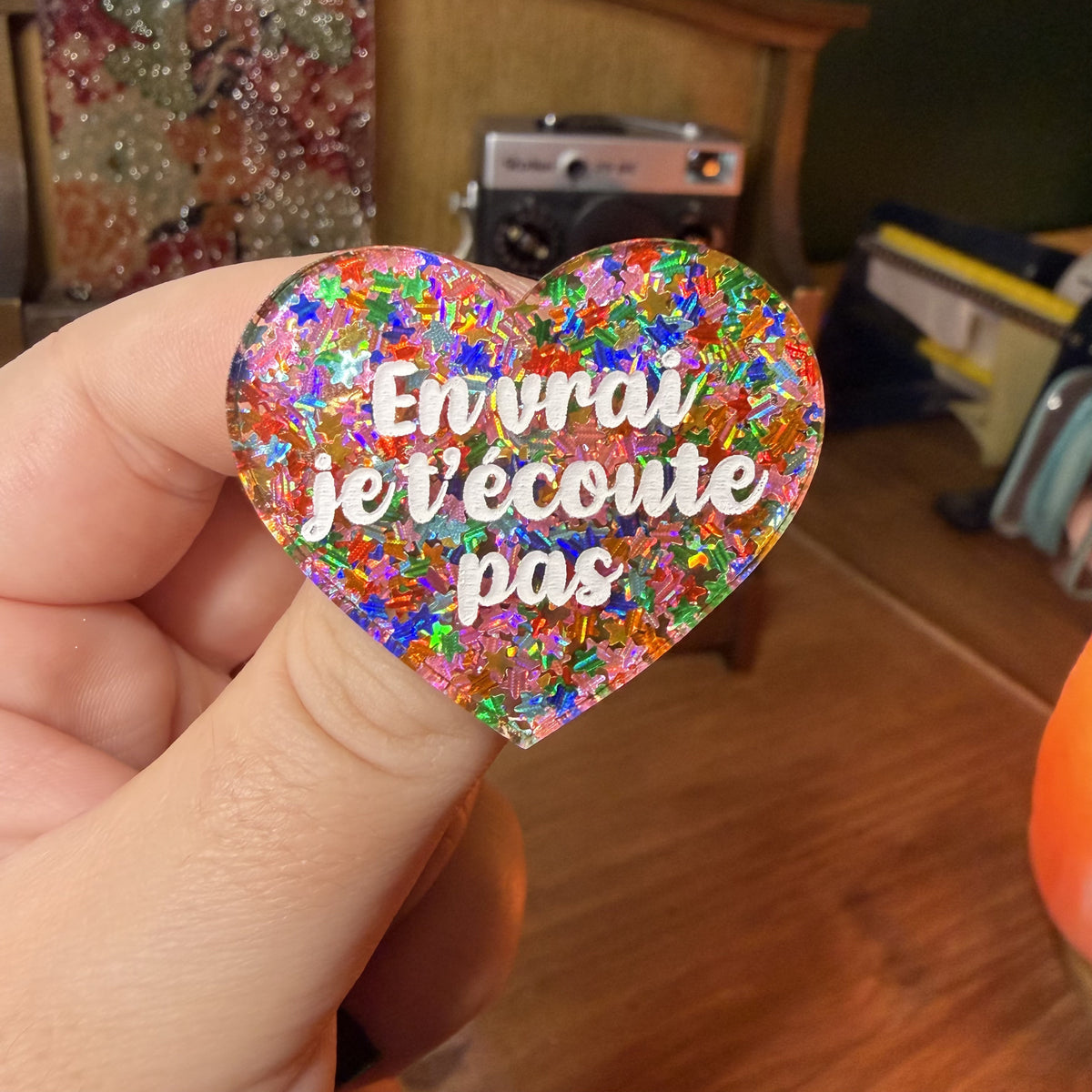 Broche "En vrai je t'écoute pas" en acrylique semi transparente avec des étoiles multicolores
