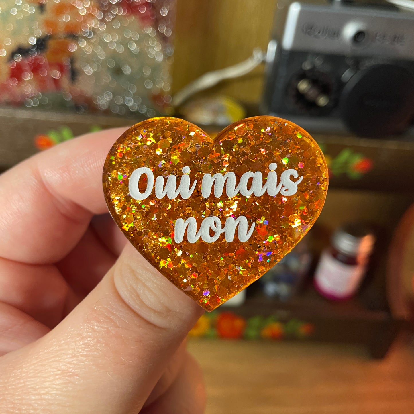 Broche "Oui mais non" en acrylique semi transparente à paillettes oranges