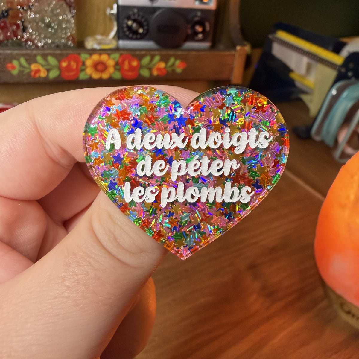 Broche "A deux doigts de péter les plombs" en acrylique semi transparente avec des étoiles multicolores