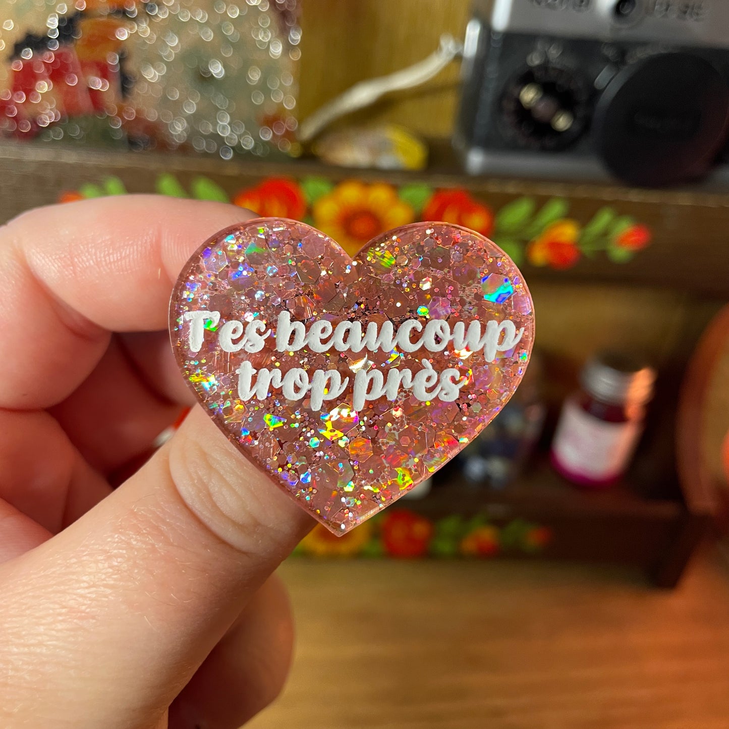 Broche "T'es beaucoup trop près" en acrylique semi transparente à paillettes corail