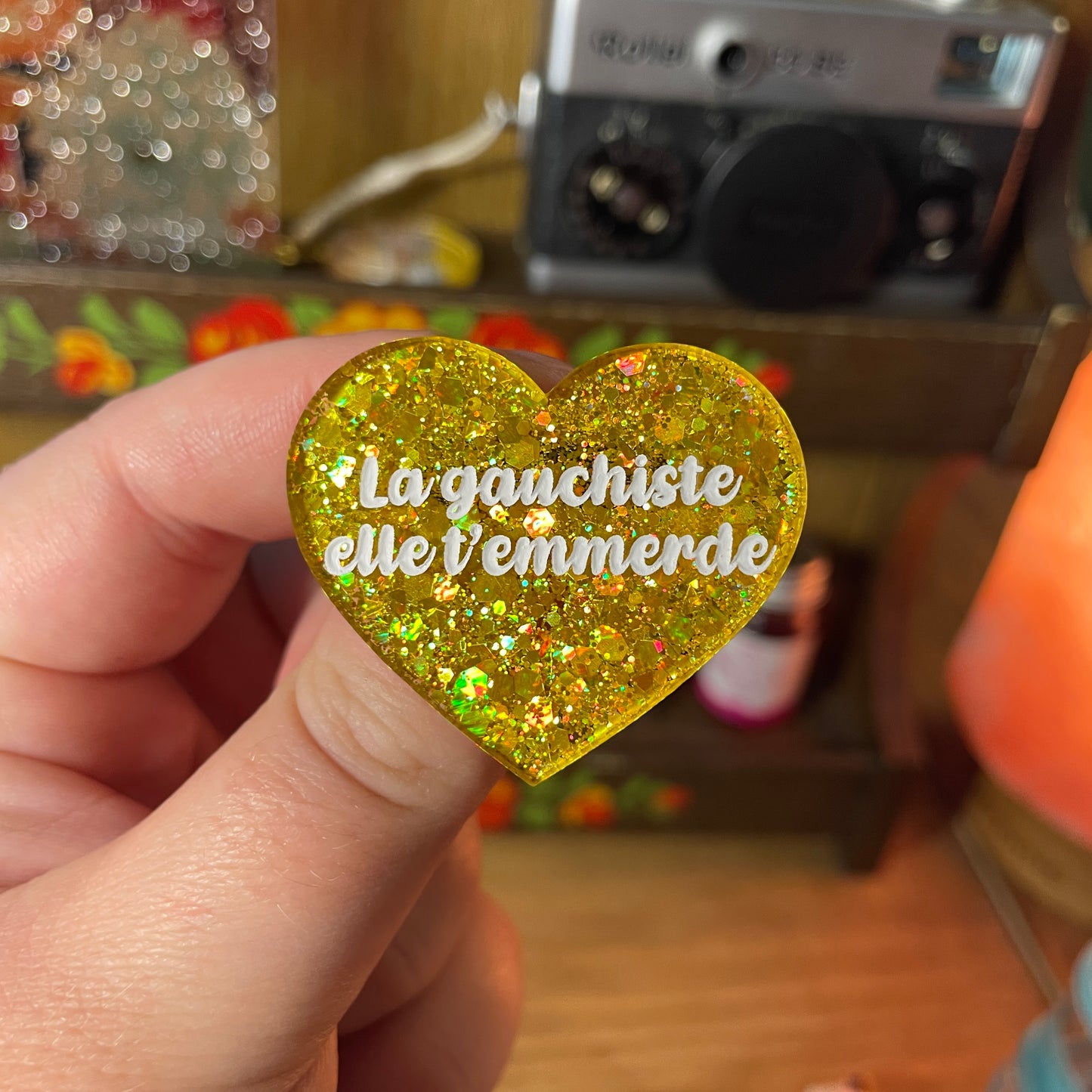 Broche "La gauchiste elle t'emmerde" en acrylique semi transparente à paillettes jaunes