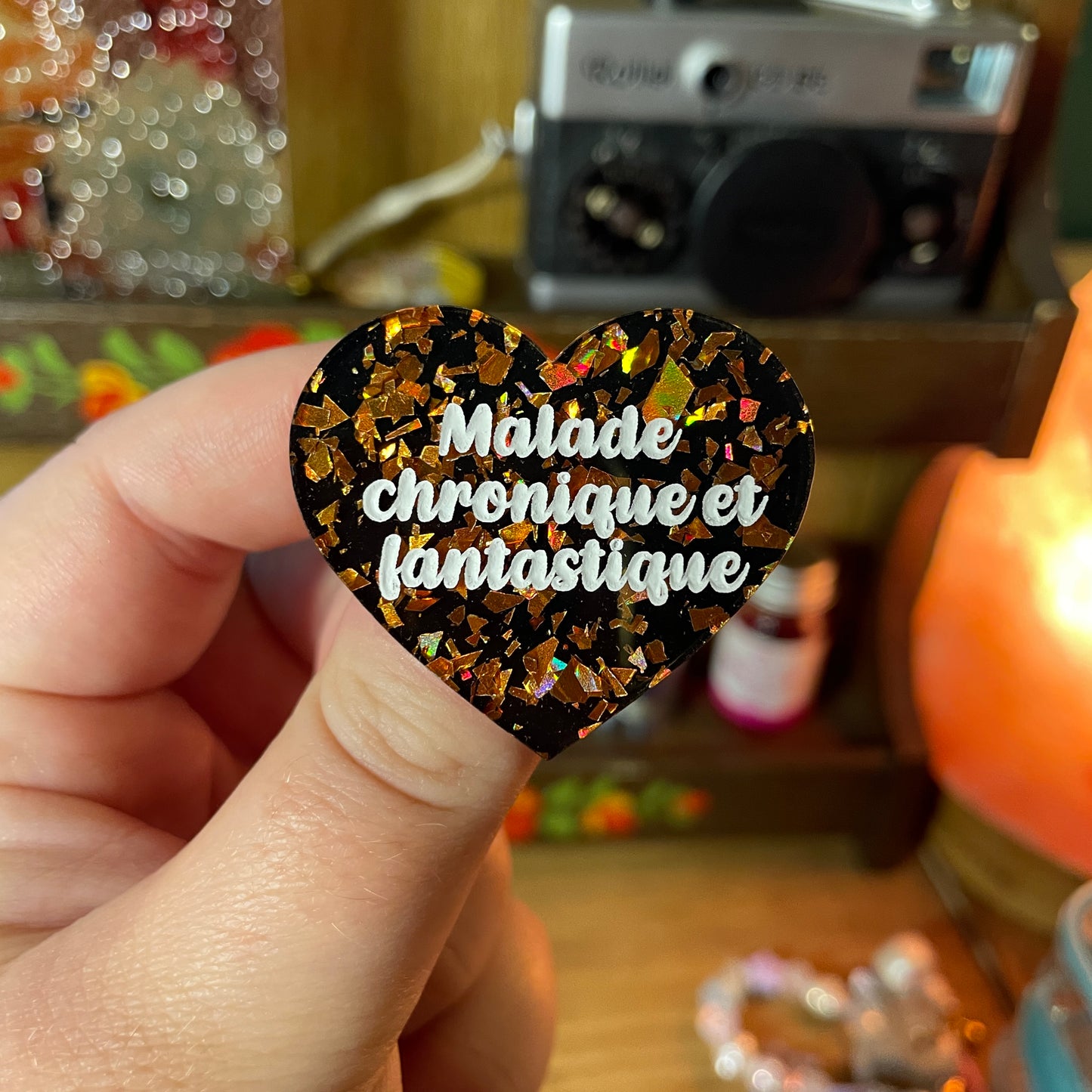 Broche "Malade chronique et fantastique" en acrylique noire avec des éclats de confettis oranges