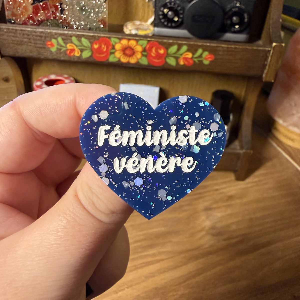 Broche "Féministe vénère" en acrylique bleue avec des confettis argentés