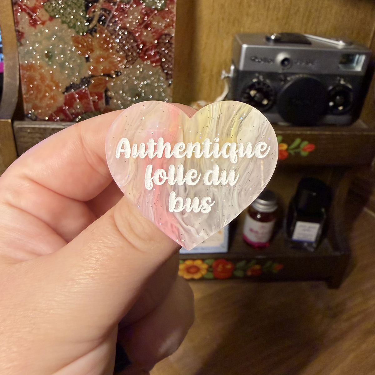 Broche "Authentique folle du bus" en acrylique semi transparente marbrée corail, orange et jaune à paillettes