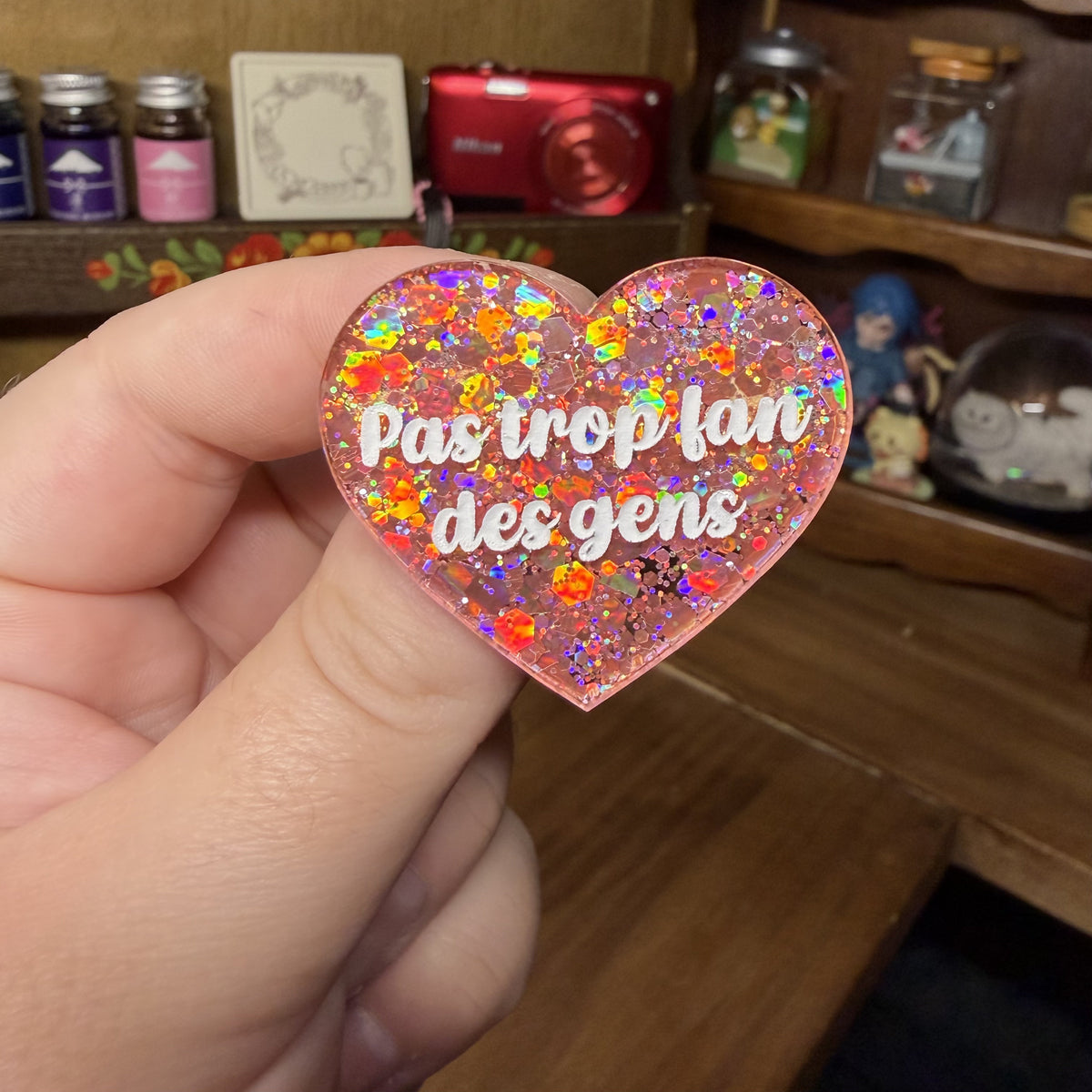 Broche "Pas trop fan des gens" en acrylique semi transparente avec des paillettes corail
