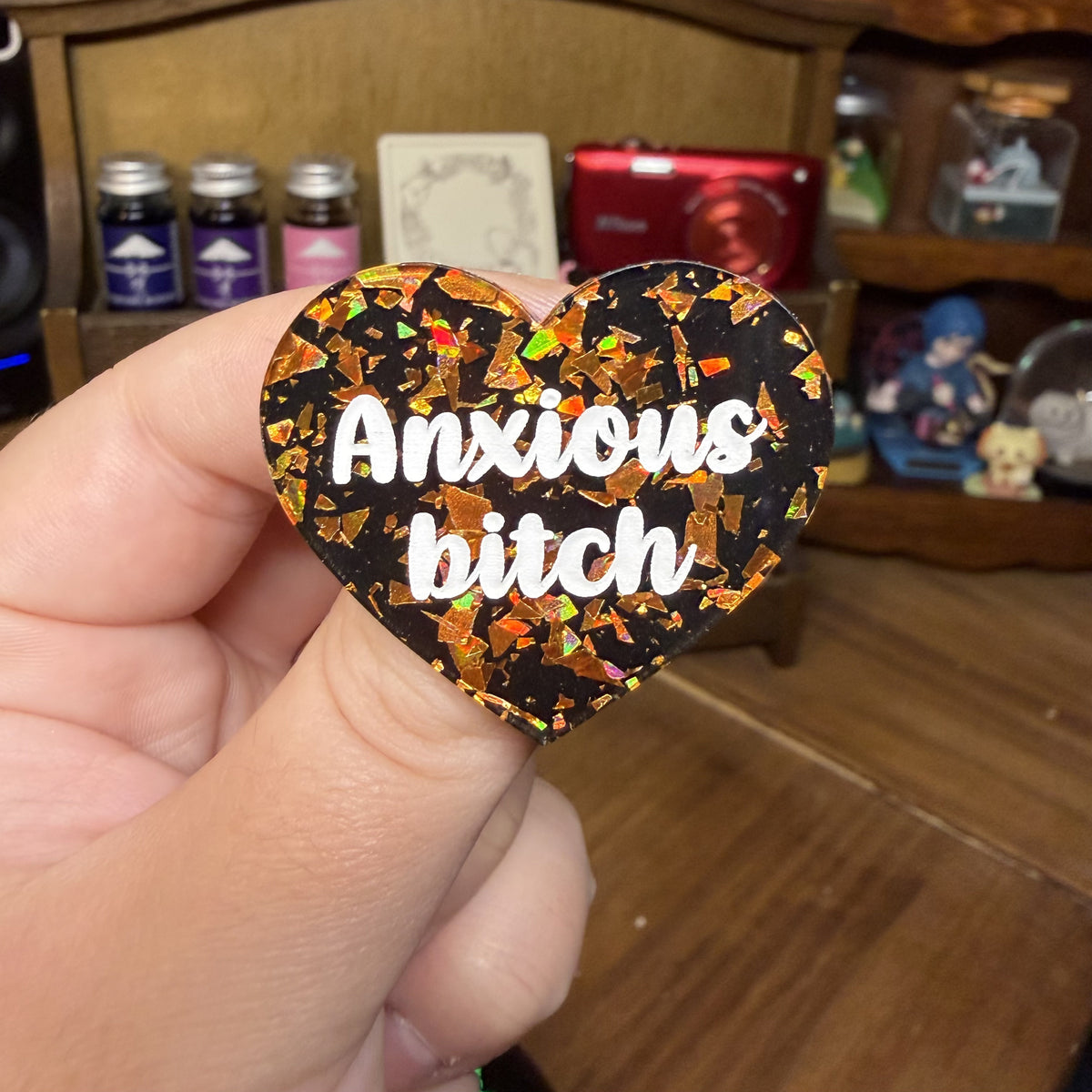 Broche "Anxious bitch" en acrylique noire avec des éclats de confettis oranges
