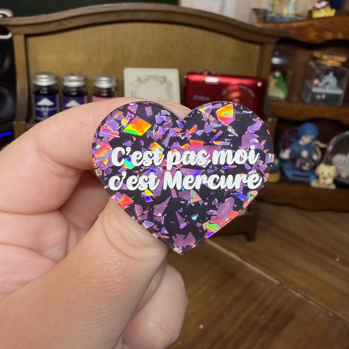 Broche "C'est pas moi c'est Mercure" en acrylique noire avec des éclats de confettis roses