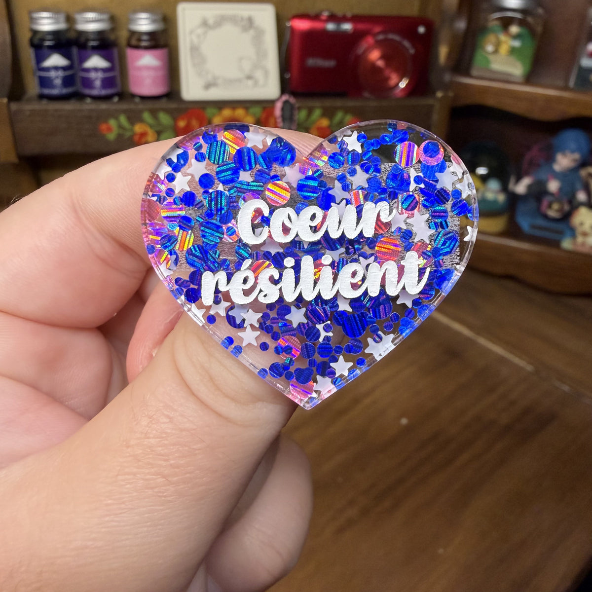 Broche "Coeur résilient" en acrylique semi transparente avec des confettis bleus, roses et blancs