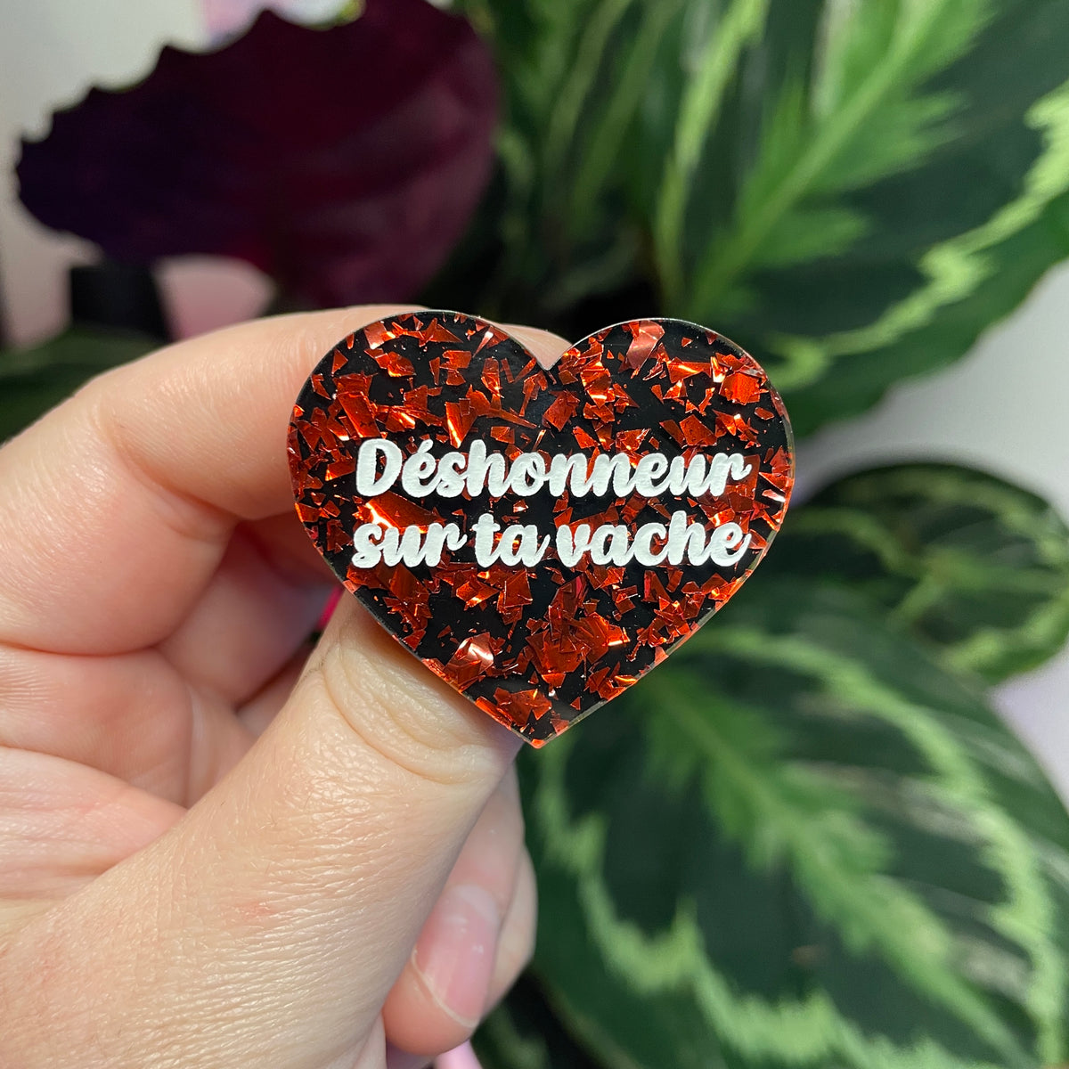 Broche "Déshonneur sur ta vache" en acrylique noire avec des éclats de confettis rouges et roses