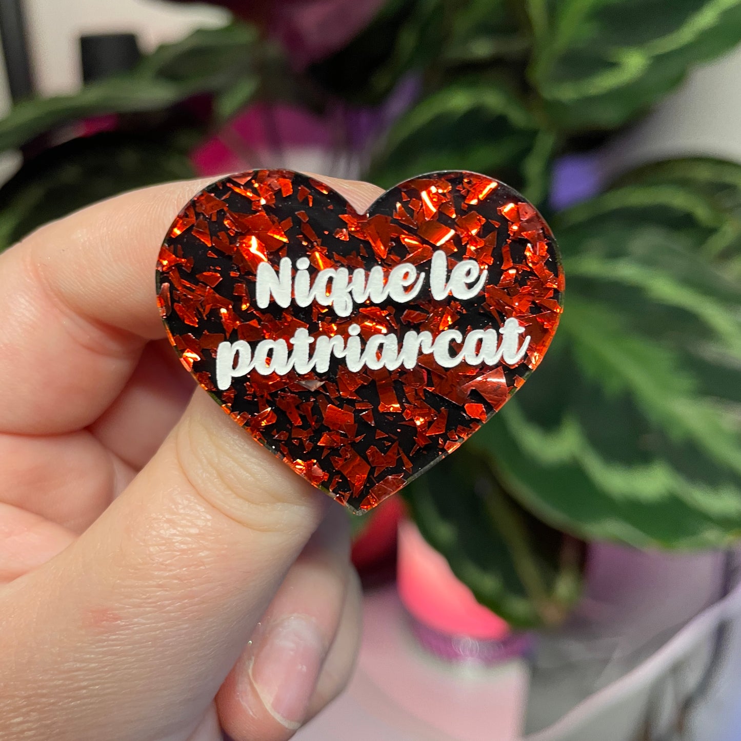 Broche "Nique le patriarcat" en acrylique noire avec des éclats de confettis rouges et roses