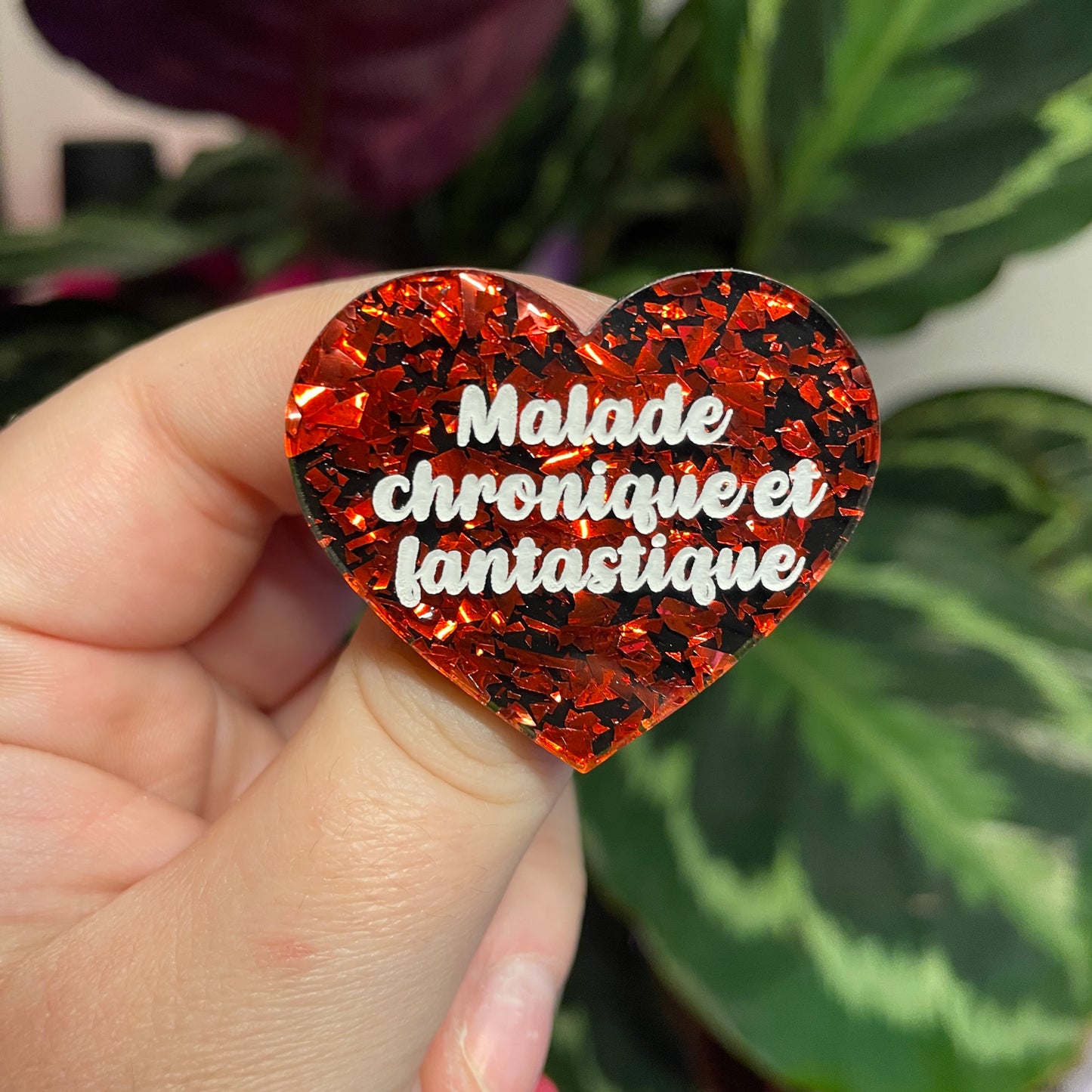 Broche "Malade chronique et fantastique" en acrylique noire avec des éclats de confettis rouges