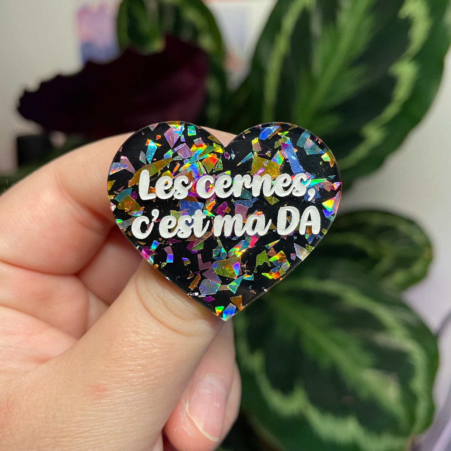 Broche "Les cernes c'est ma DA" en acrylique noire avec des éclats de confettis multicolores