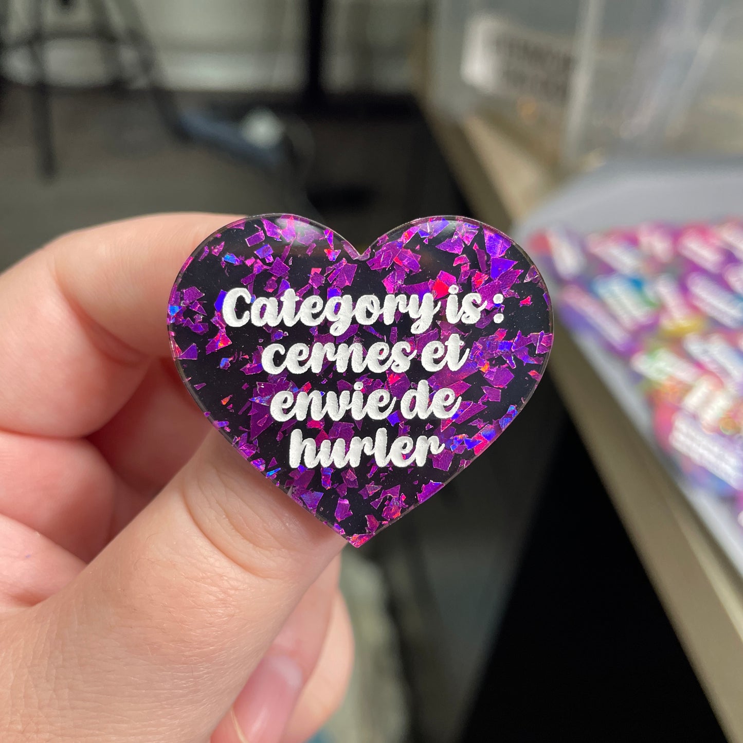 Broche "Category is : cernes et envie de hurler" en acrylique noire avec des éclats de confettis violets