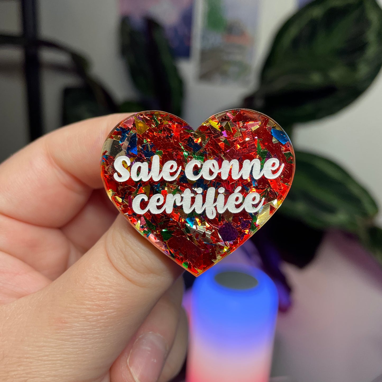 Broche "Sale conne certifiée" en acrylique transparente avec des confettis rouges et multicolores