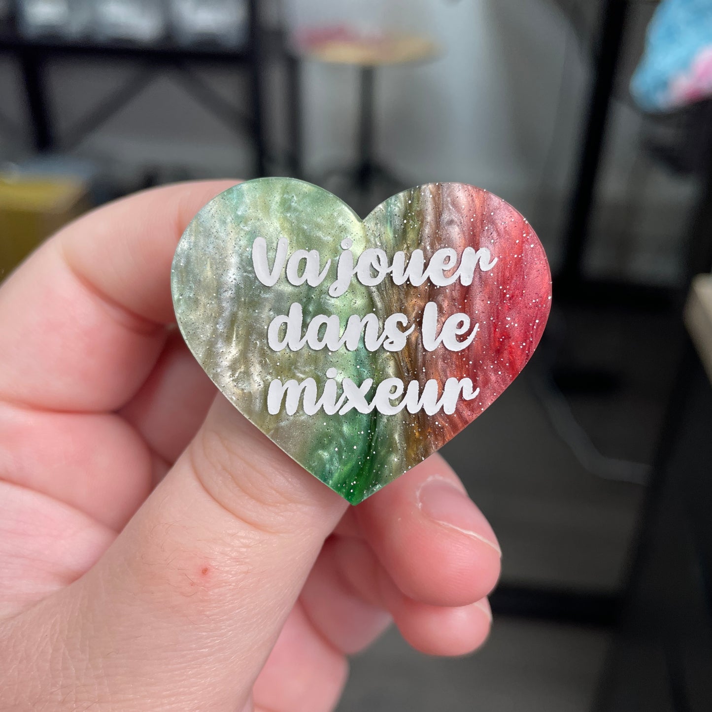 Broche "Va jouer dans le mixeur" en acrylique marbrée verte, rouge, marron et blanche à paillettes