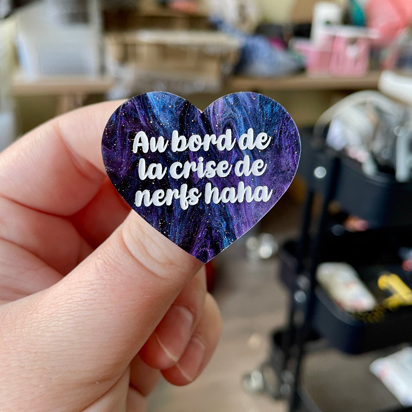 Broche "Au bord de la crise de nerfs haha" en acrylique marbrée noire, bleue et violette à paillettes