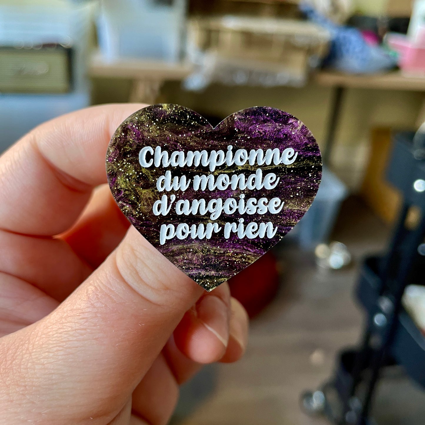 Broche "Championne du monde d'angoisse pour rien" en acrylique marbrée noire, violette et dorée à paillettes