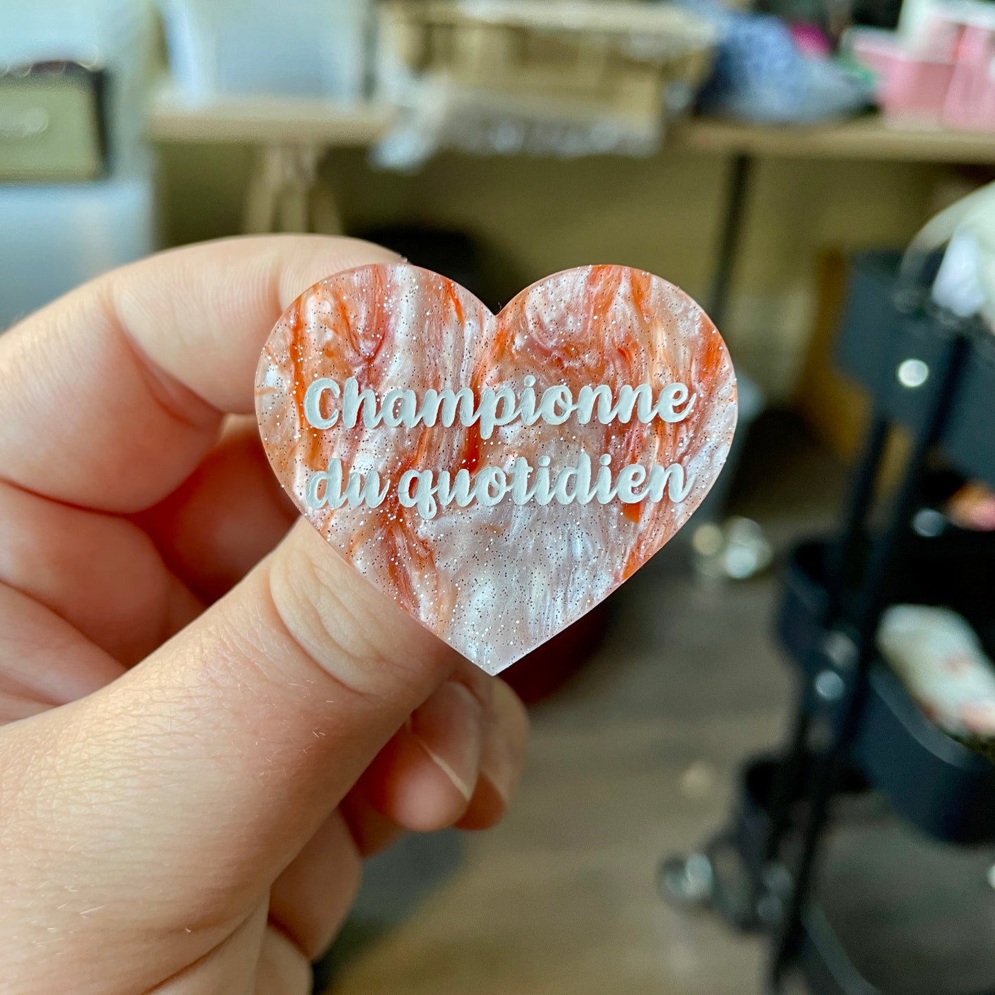 Broche "Championne du quotidien" en acrylique marbrée orange et blanche à paillettes