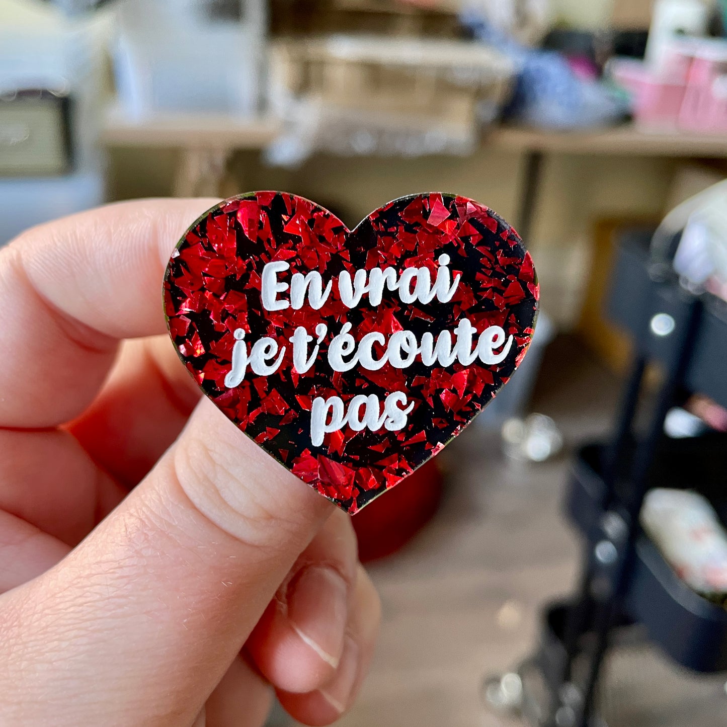 Broche "En vrai je t'écoute pas" en acrylique noire avec des éclats de confettis rouges