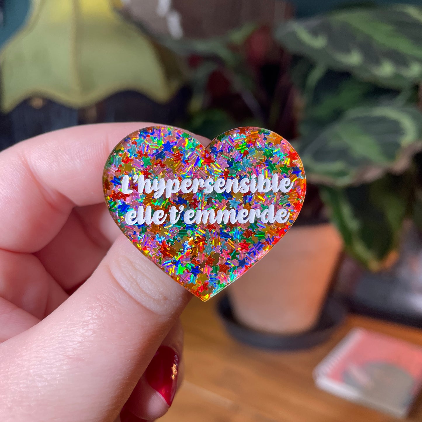 Broche "L'hypersensible elle t'emmerde" en acrylique semi transparente avec des étoiles multicolores