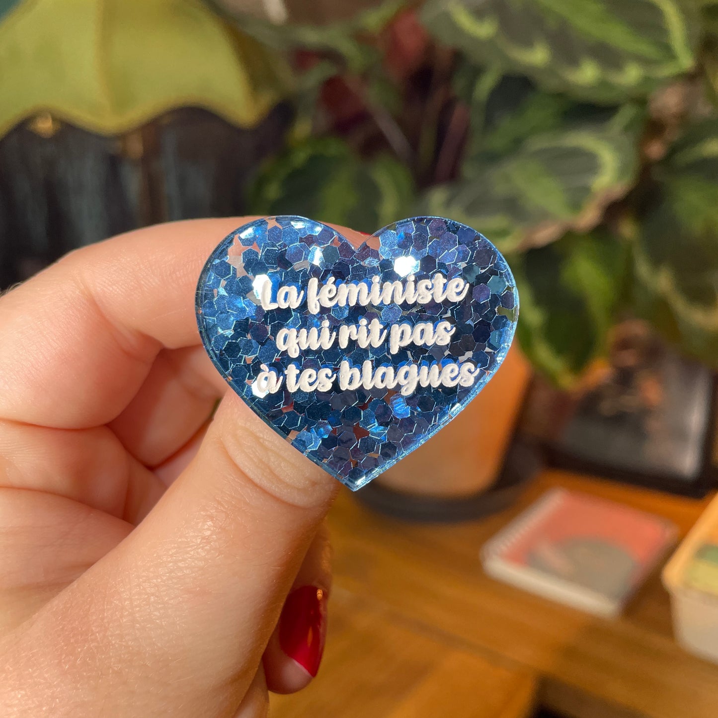 Broche "La féministe qui rit pas à tes blagues" en acrylique semi transparente avec des confettis bleus