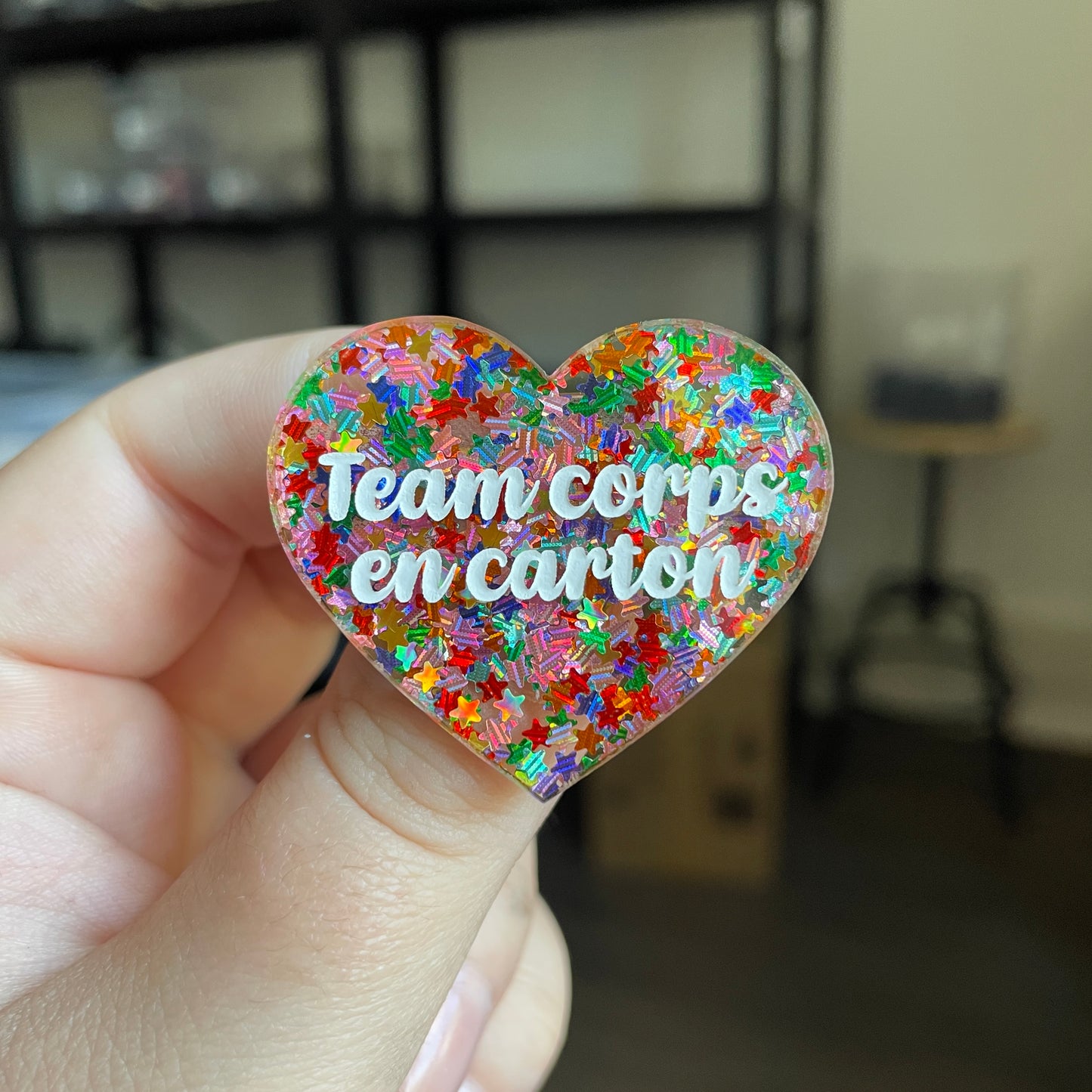 Broche "Team corps en carton" en acrylique semi transparente avec des confettis étoiles multicolores