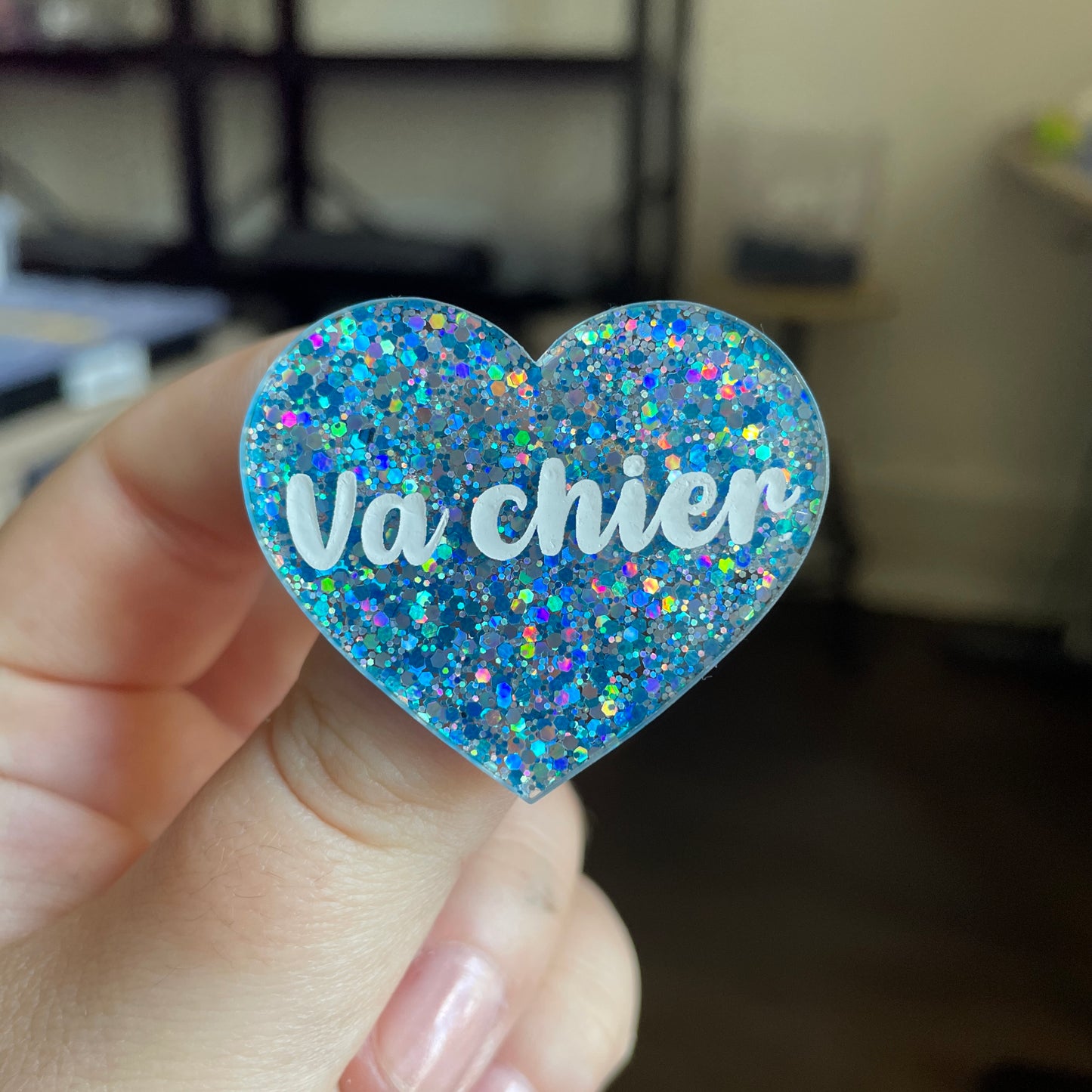 Broche "Va chier" en acrylique semi transparente avec des paillettes bleues et argentées