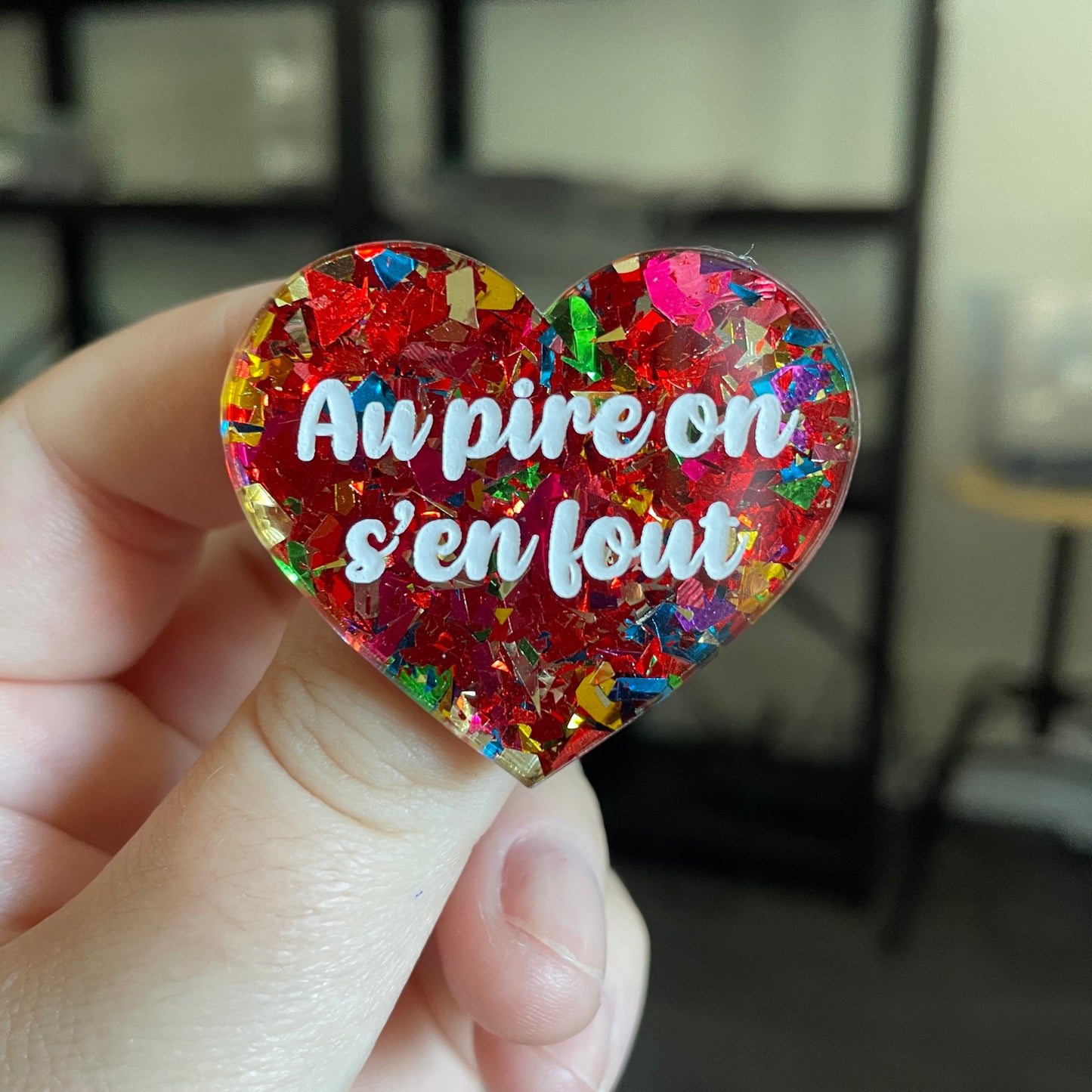 Broche "Au pire on s'en fout" en acrylique transparente avec des confettis rouges et multicolores