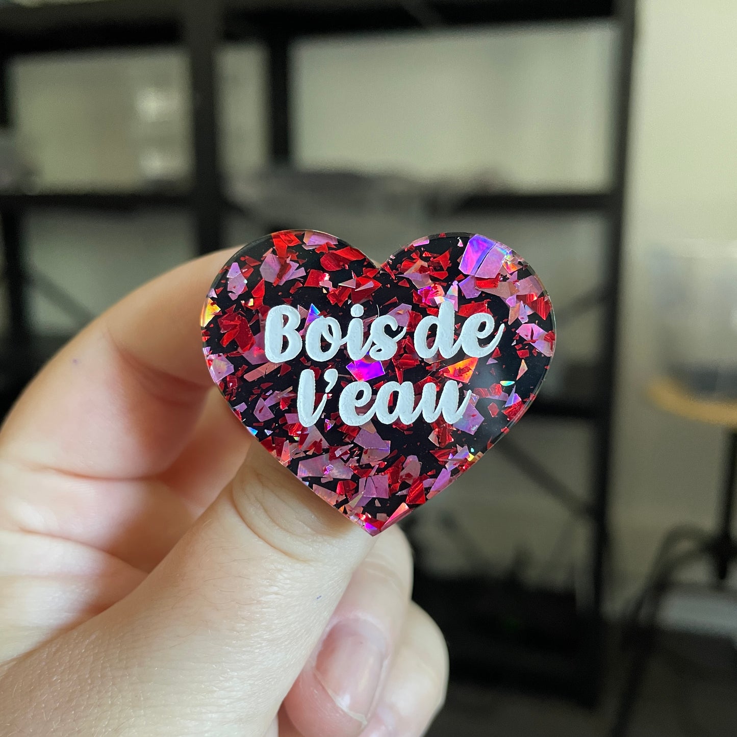 Broche "Bois de l'eau" en acrylique noire avec des éclats de confettis rouges et roses