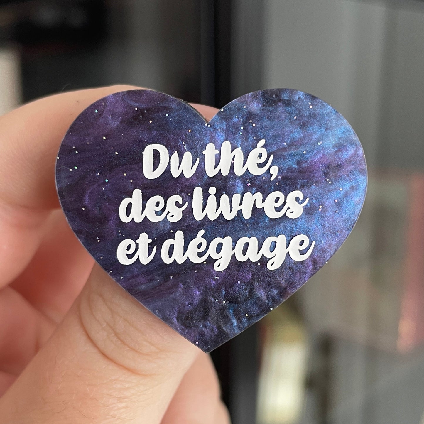 Broche "Du thé, des livres et dégage" en acrylique marbrée bleue, noire et violette à paillettes