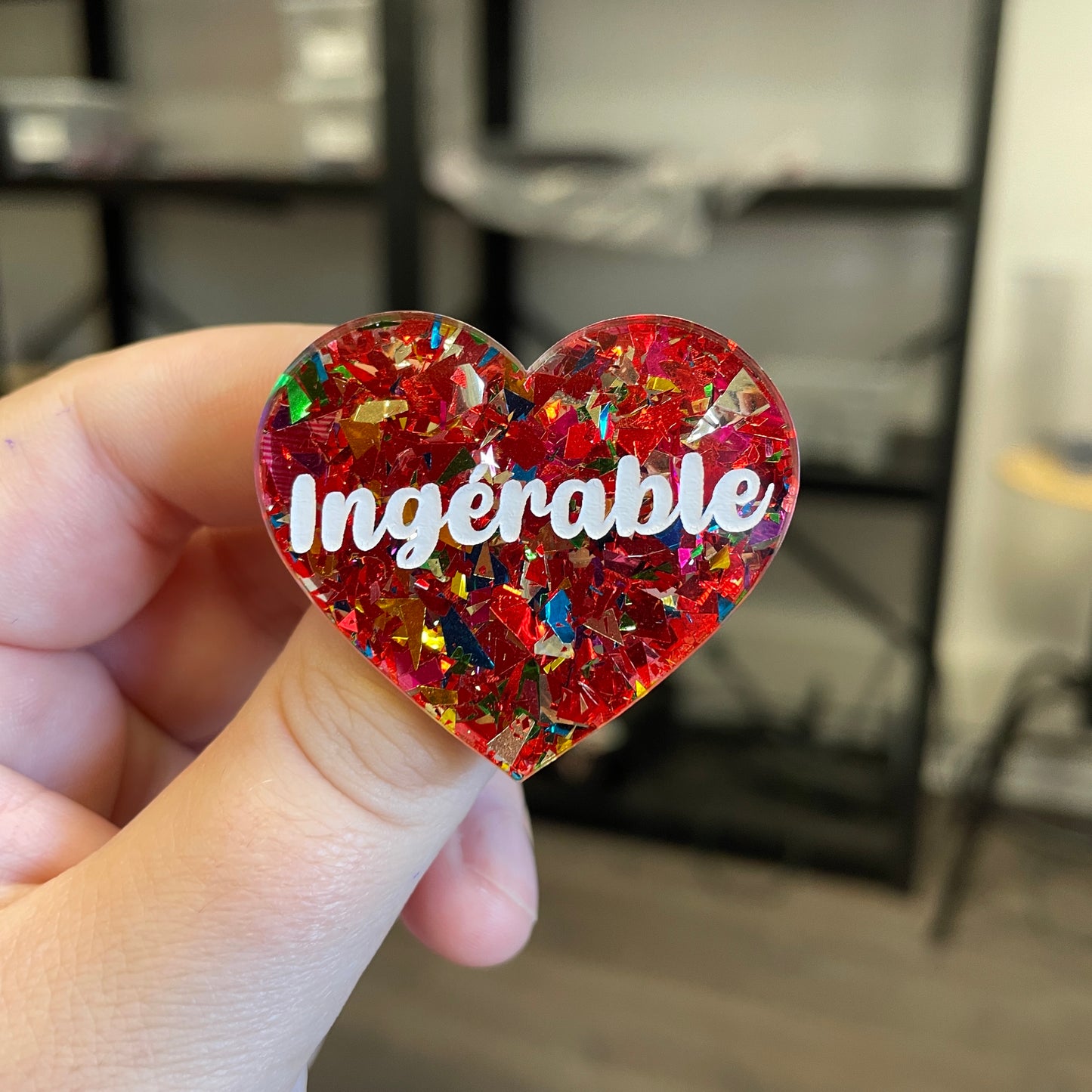 Broche "Ingérable" en acrylique transparente avec des éclats de confettis rouges et multicolores