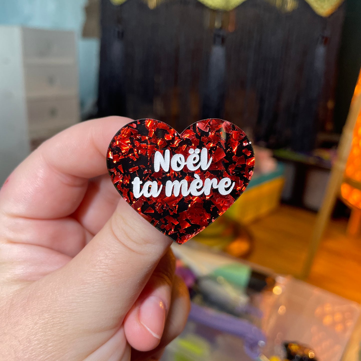 Broche "Noël ta mère" en acrylique noire avec des éclats de confettis rouges