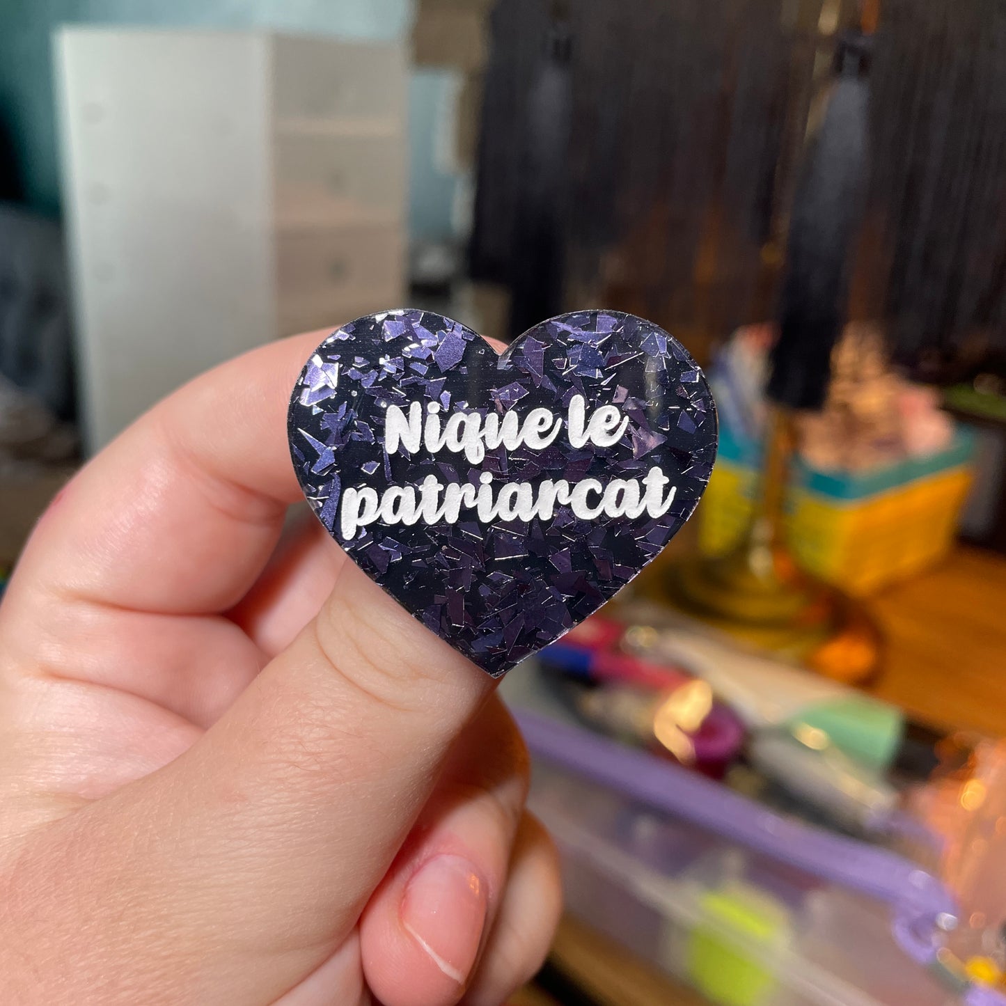 Broche "Nique le patriarcat" en acrylique noire avec des éclats de confettis gris