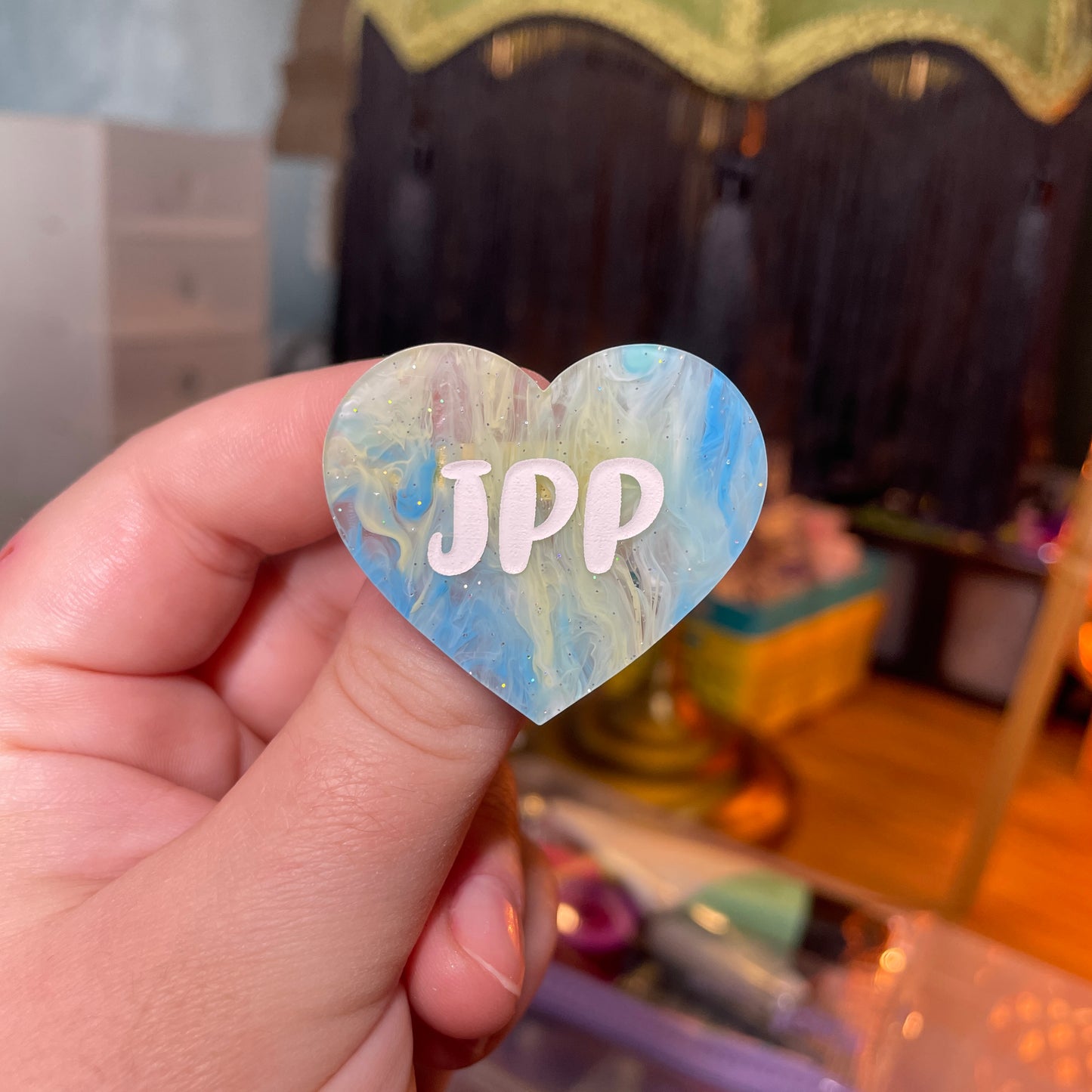 Broche "JPP" en acrylique semi transparente marbrée bleue, jaune et blanche à paillettes