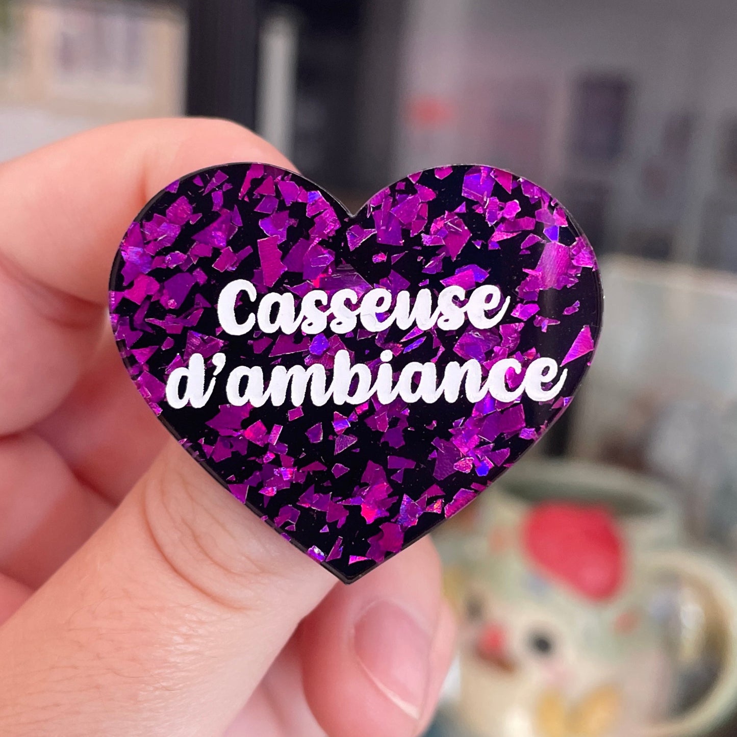 Broche "Casseuse d'ambiance" en acrylique noire avec des éclats de confettis violets