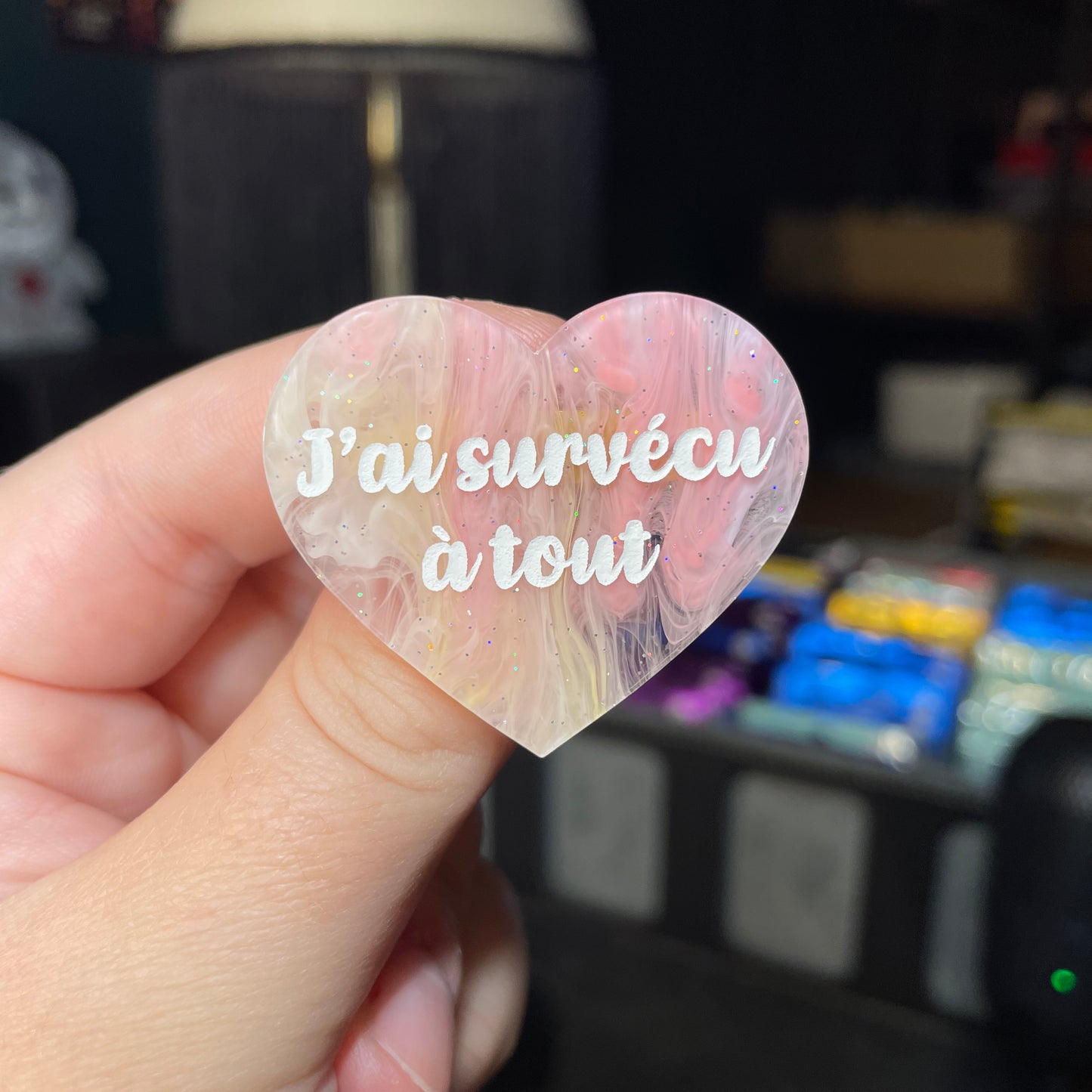 Broche "J'ai survécu à tout" en acrylique semi transparente marbrée corail, orange et jaune à paillettes