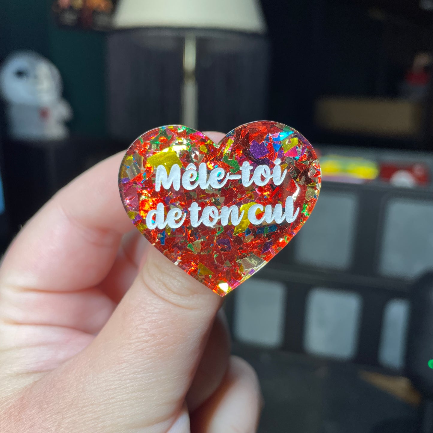 Broche "Mêle-toi de ton cul" en acrylique transparente avec des éclats de confettis rouges et multicolores