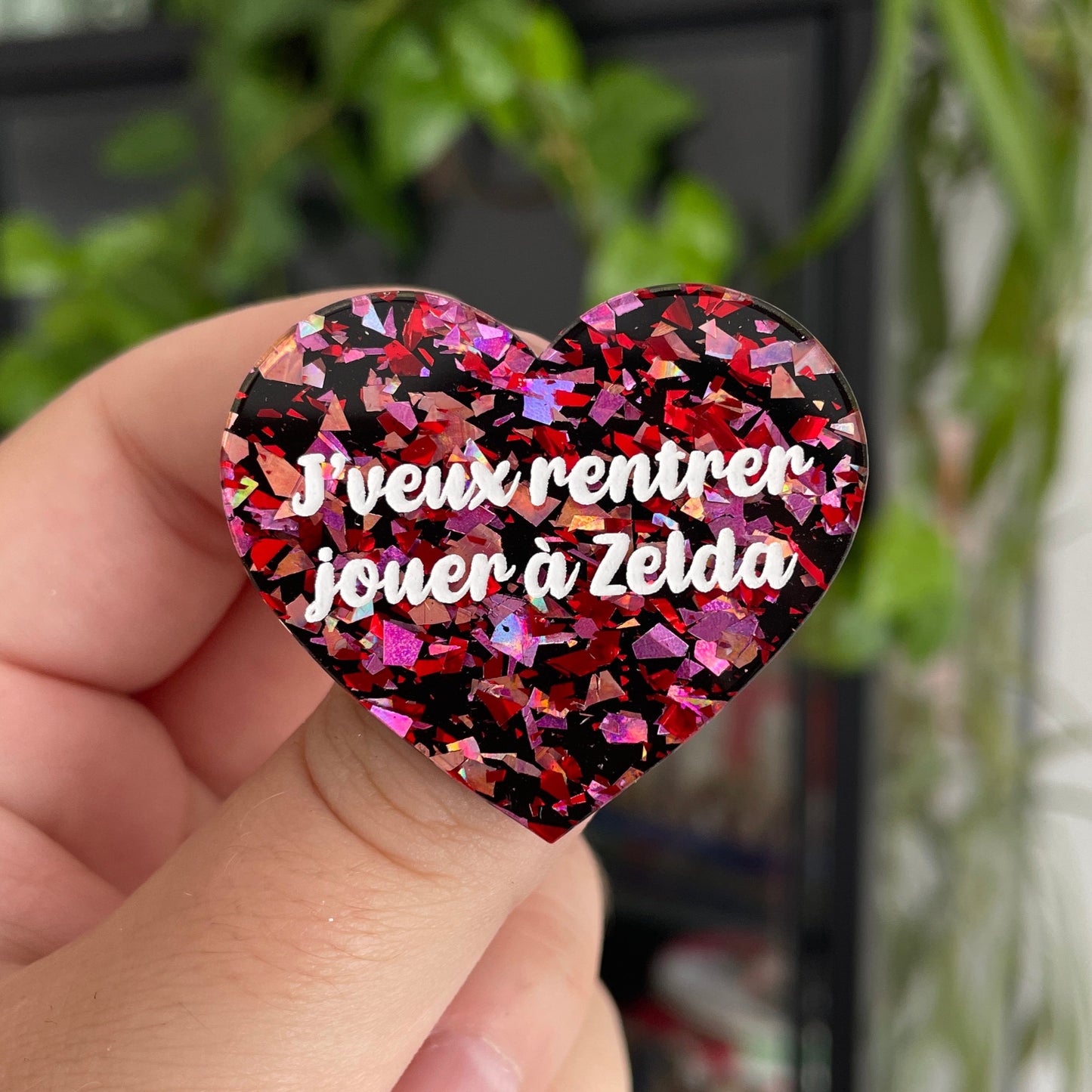 Broche "J'veux rentrer jouer à Zelda" en acrylique noire avec des éclats de confettis rouges et roses