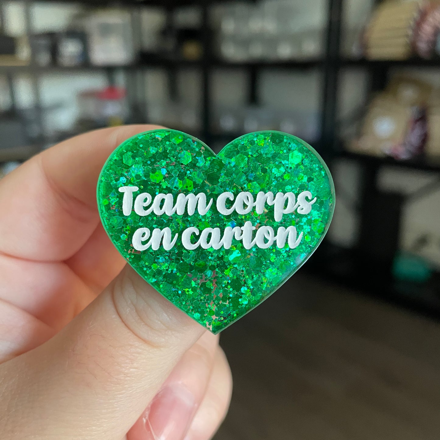 Broche "Team corps en carton" en acrylique semi transparente à paillettes vertes
