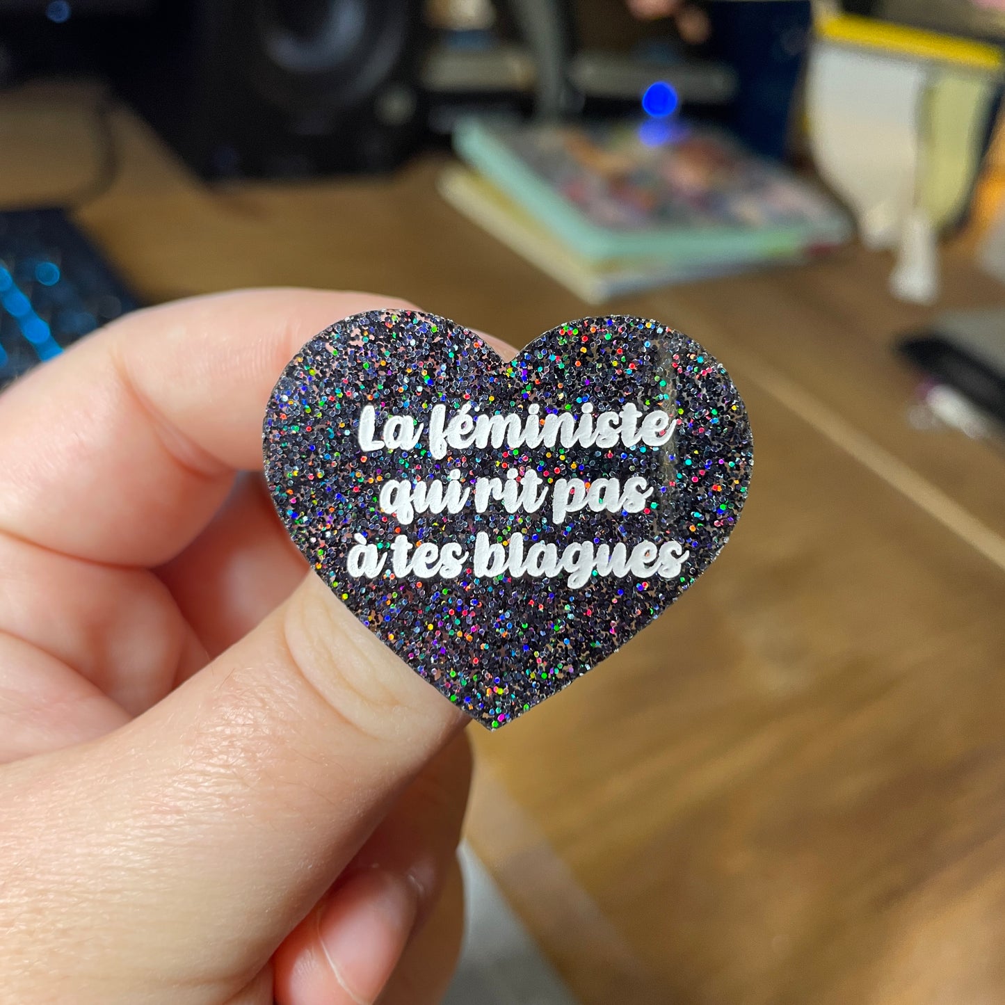 Broche "La féministe qui rit pas à tes blagues" en acrylique à paillettes noires holographiques
