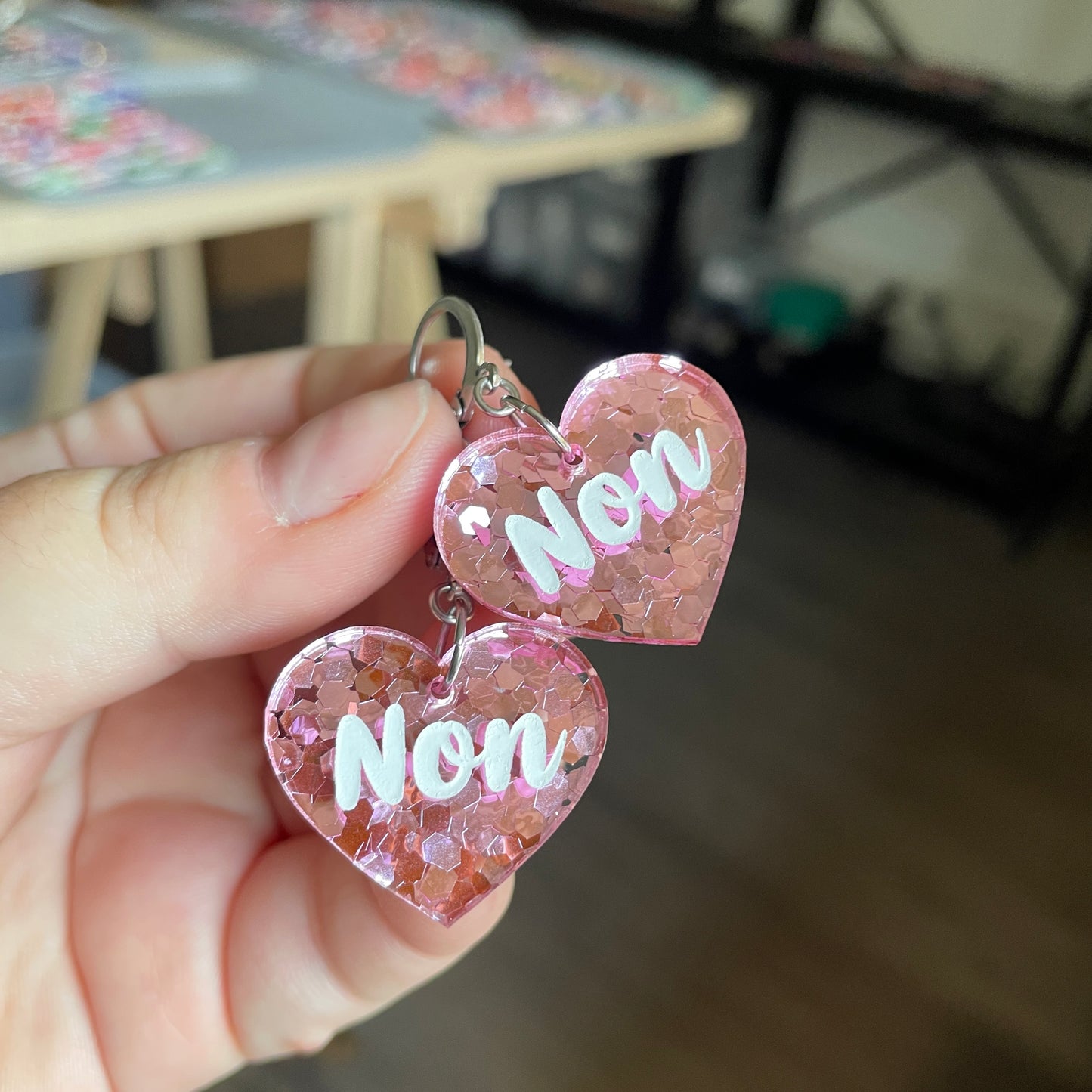 Petites boucles d'oreilles coeurs pendantes "Non" en acrylique semi transparente avec des confettis roses